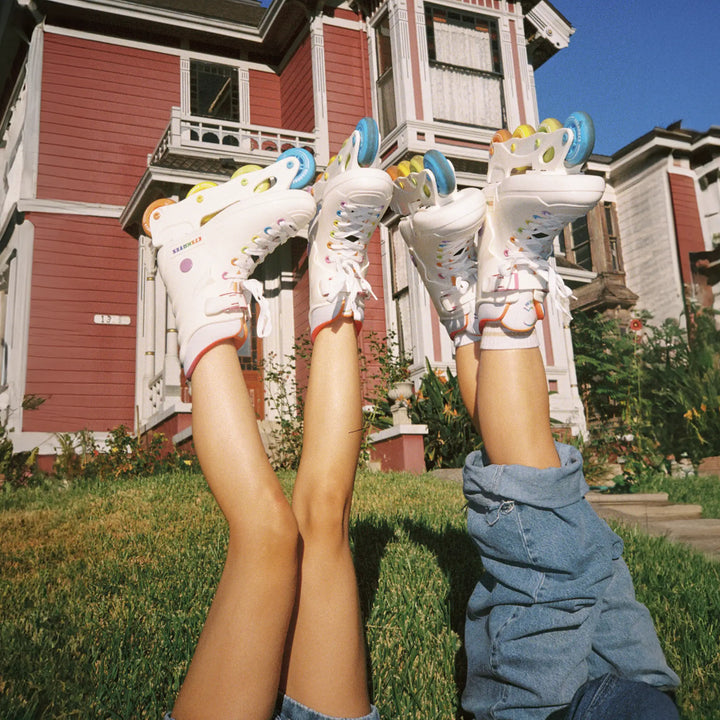 Two pairs of legs wearing roller skates in front of a house.