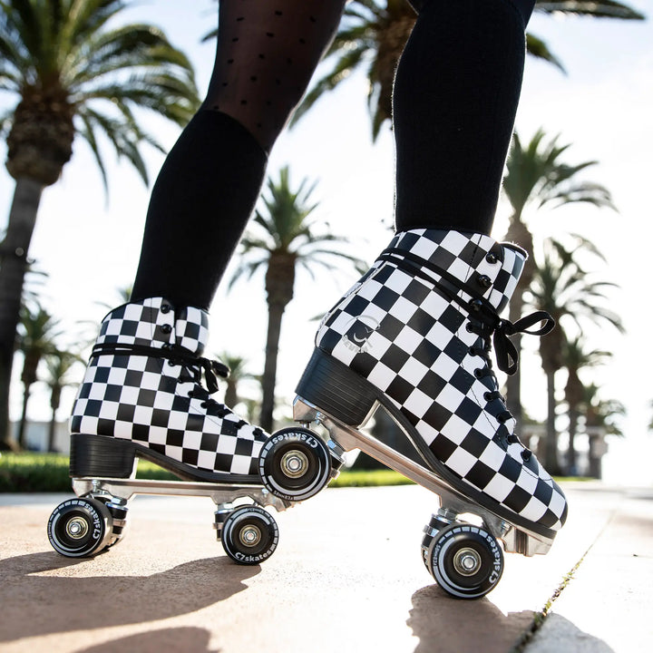 Checkered roller skates on a person with palm trees in the background