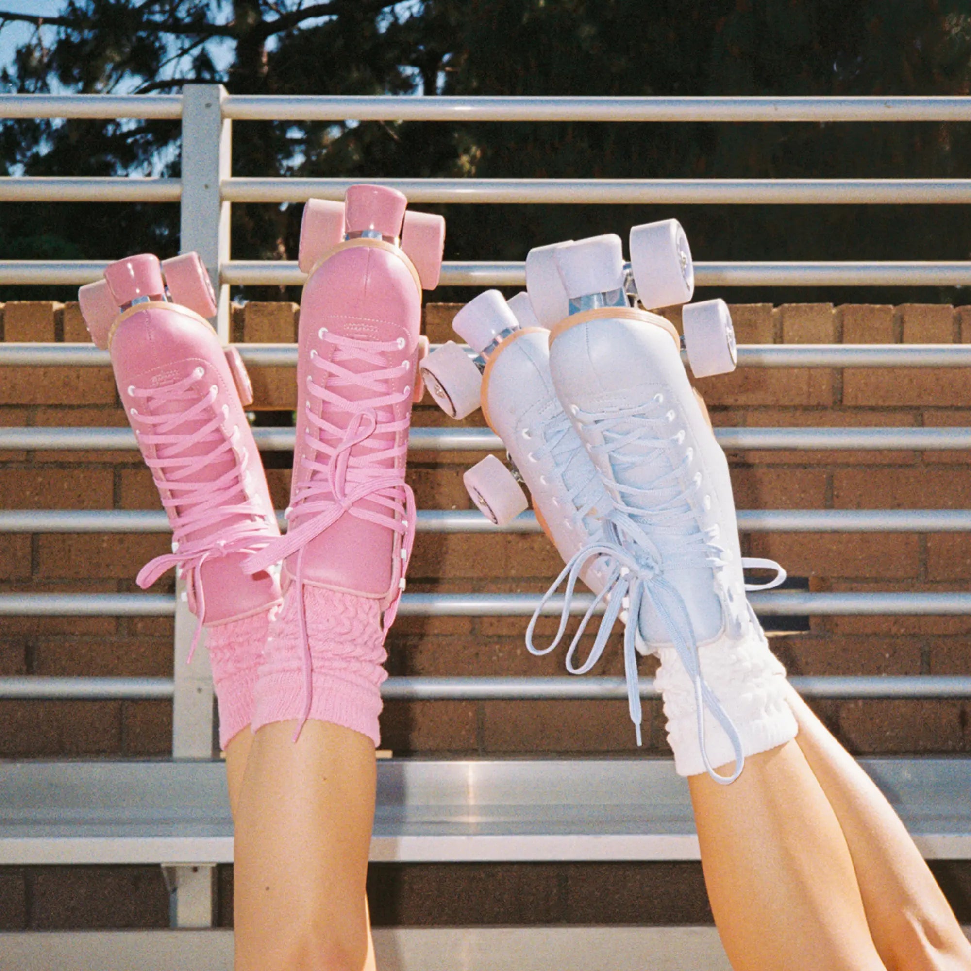 Pink and white roller skates on a person's feet with a blurred background