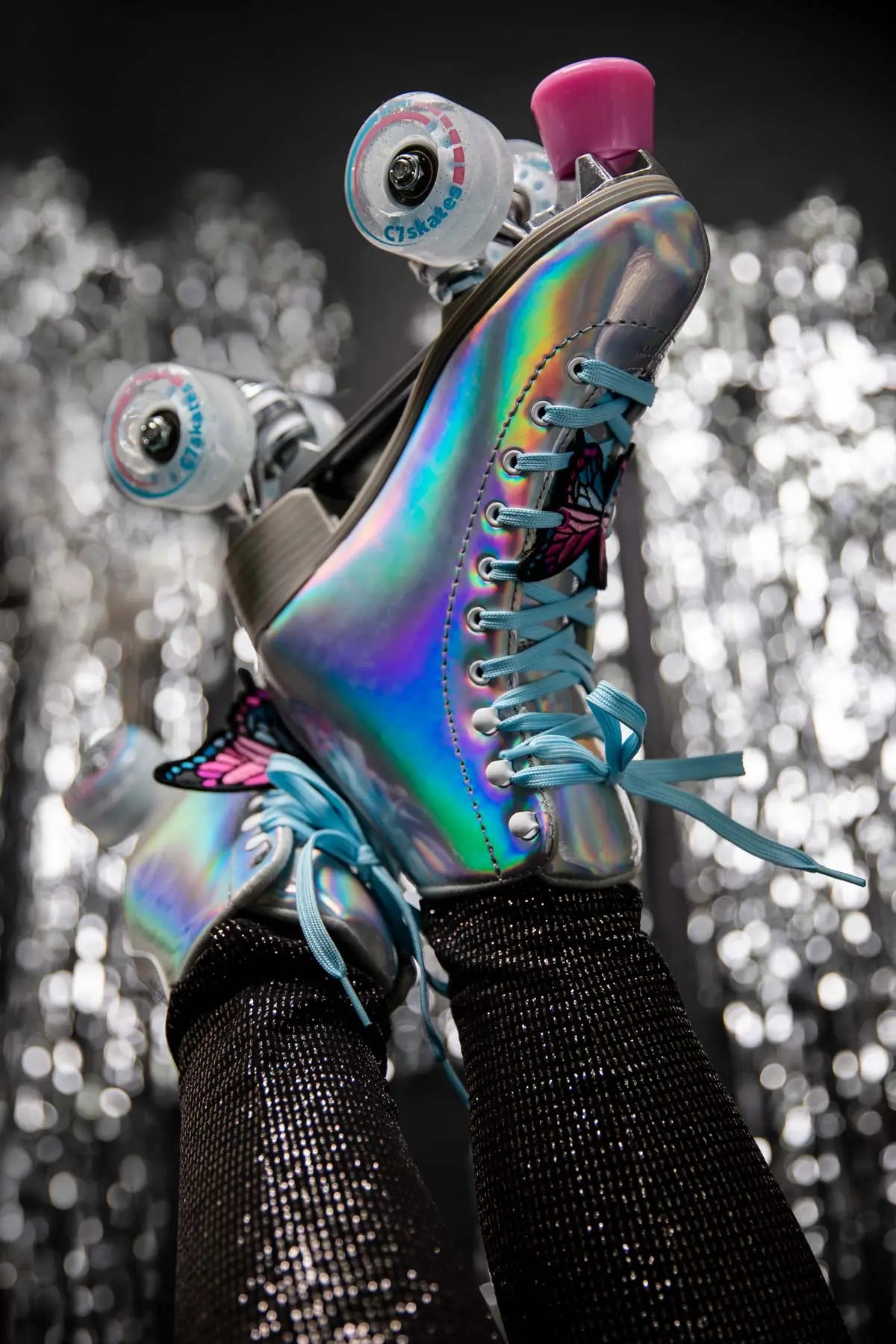 Holographic roller skates with pink top and blue laces on a blurred background