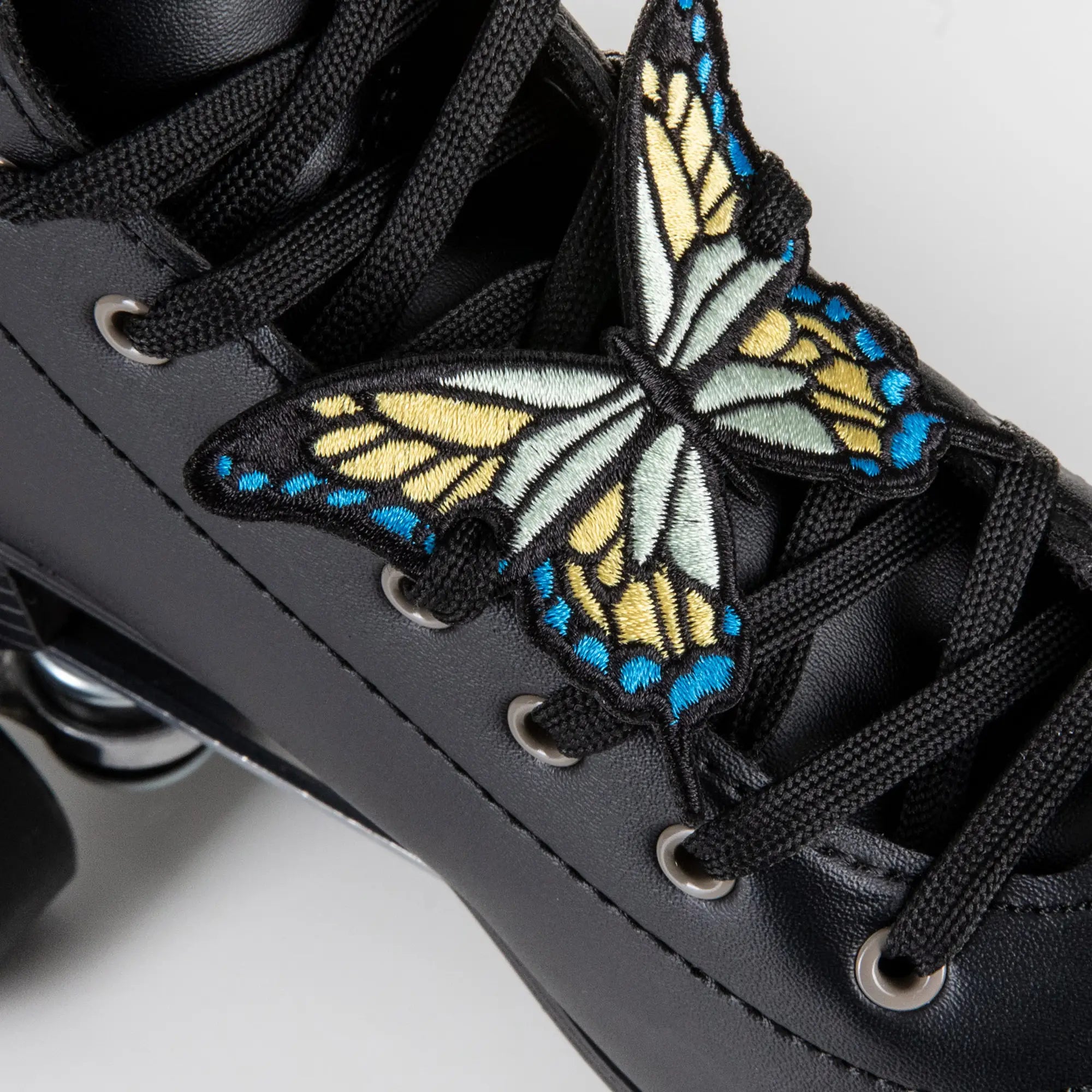 Black roller skate with a butterfly patch on a light gray background