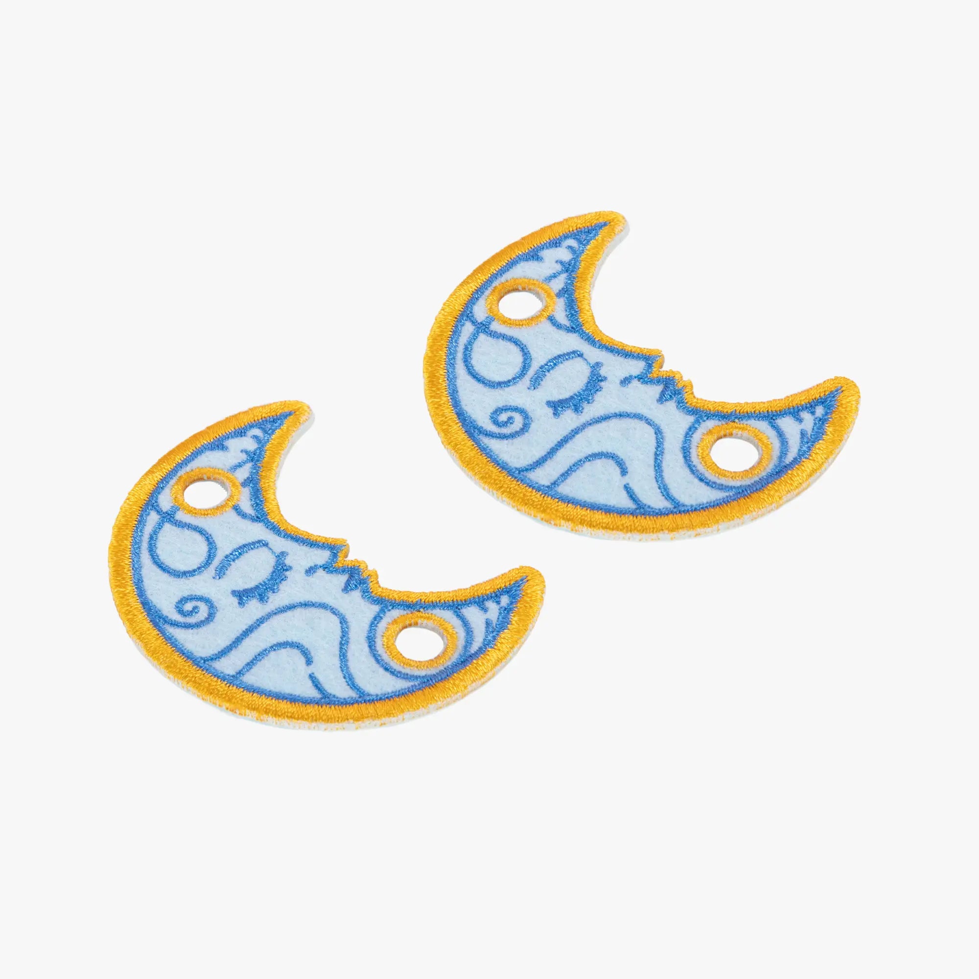 Two blue crescent moon-shaped charms with yellow outlines on a white background