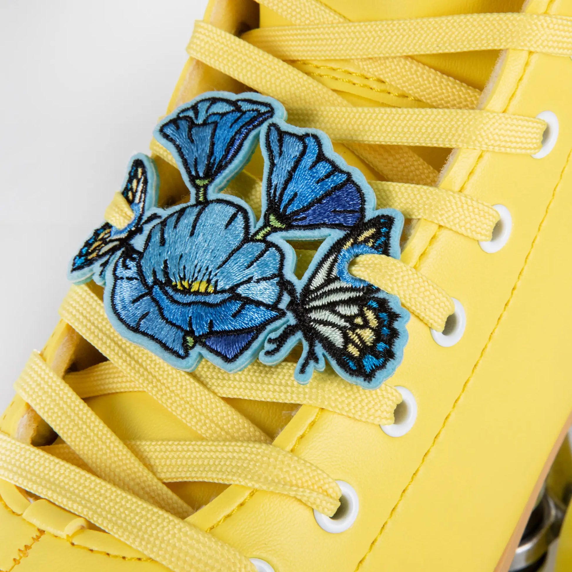 Yellow sneaker with blue floral charm on a white background