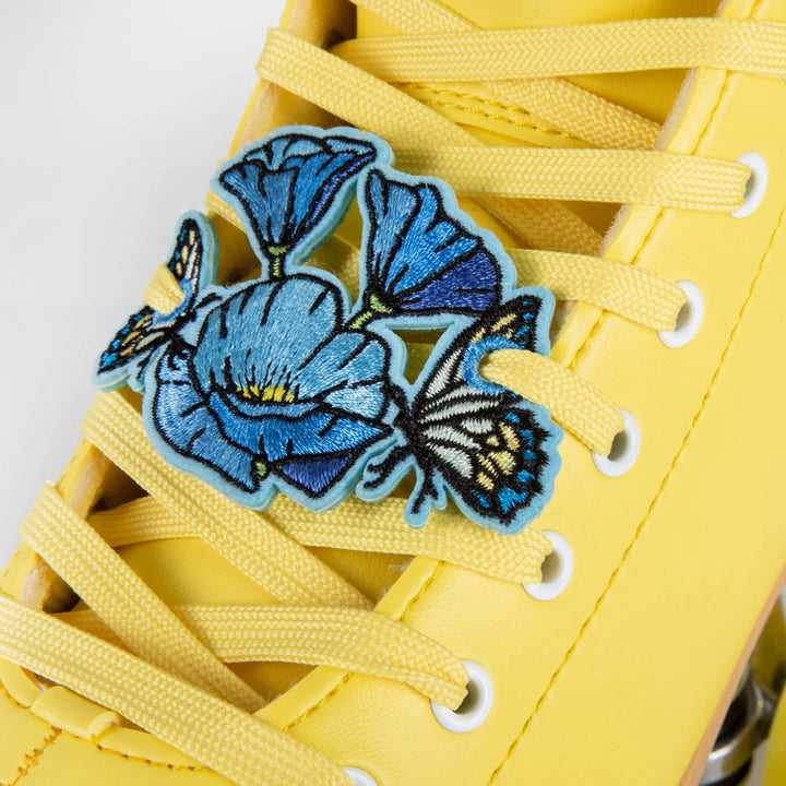 Yellow sneaker with blue floral charm on a white background