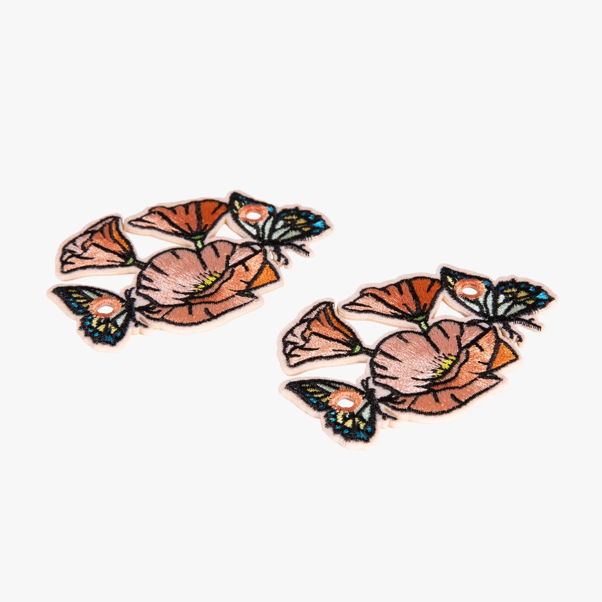 Pair of floral charms with orange flowers and green leaves on a white background
