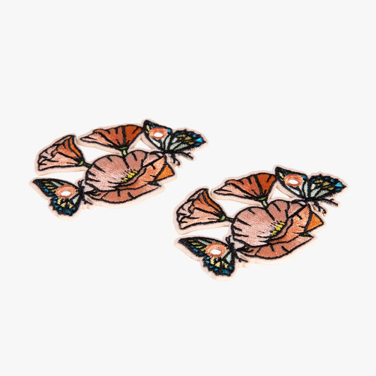 Pair of floral charms with orange flowers and green leaves on a white background