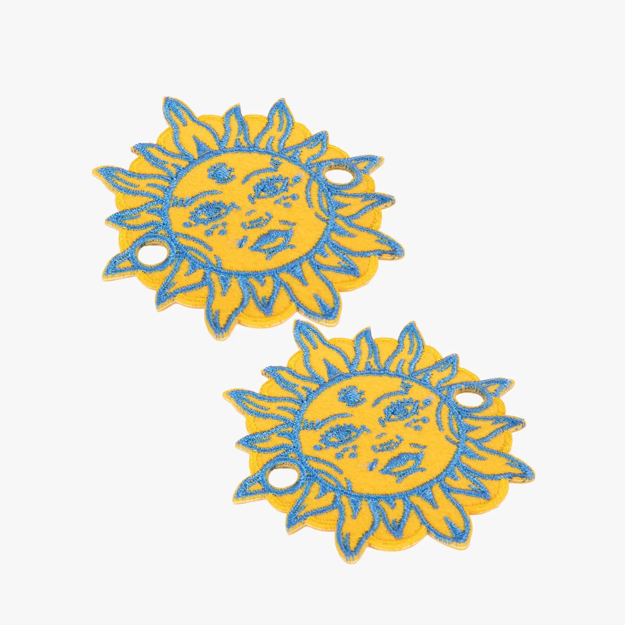 Two yellow and blue sun-shaped charms on a white background
