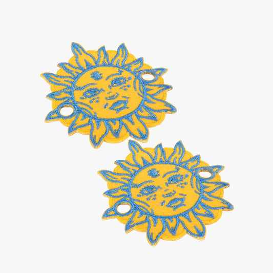Two yellow and blue sun-shaped charms on a white background