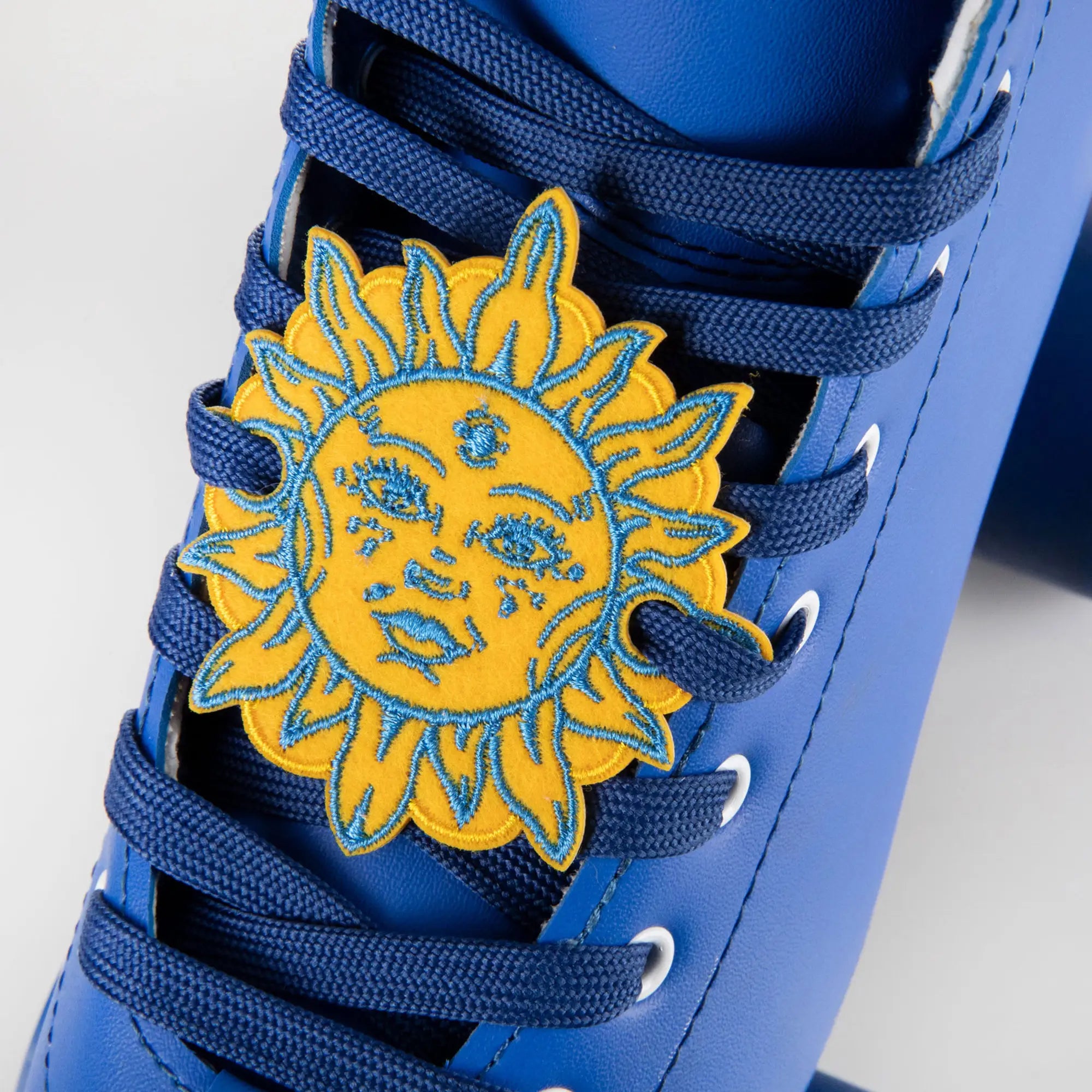 Blue sneaker with a yellow sun design charm on a white background