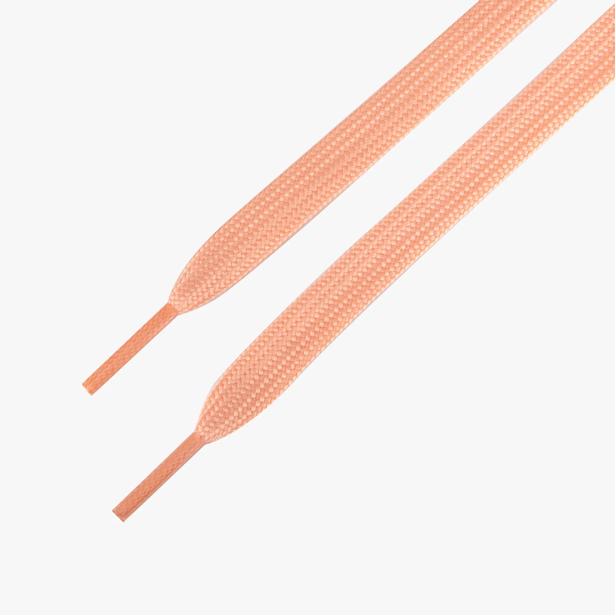 Pair of peach-colored shoelaces on a white background