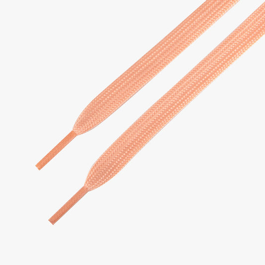 Pair of peach-colored shoelaces on a white background