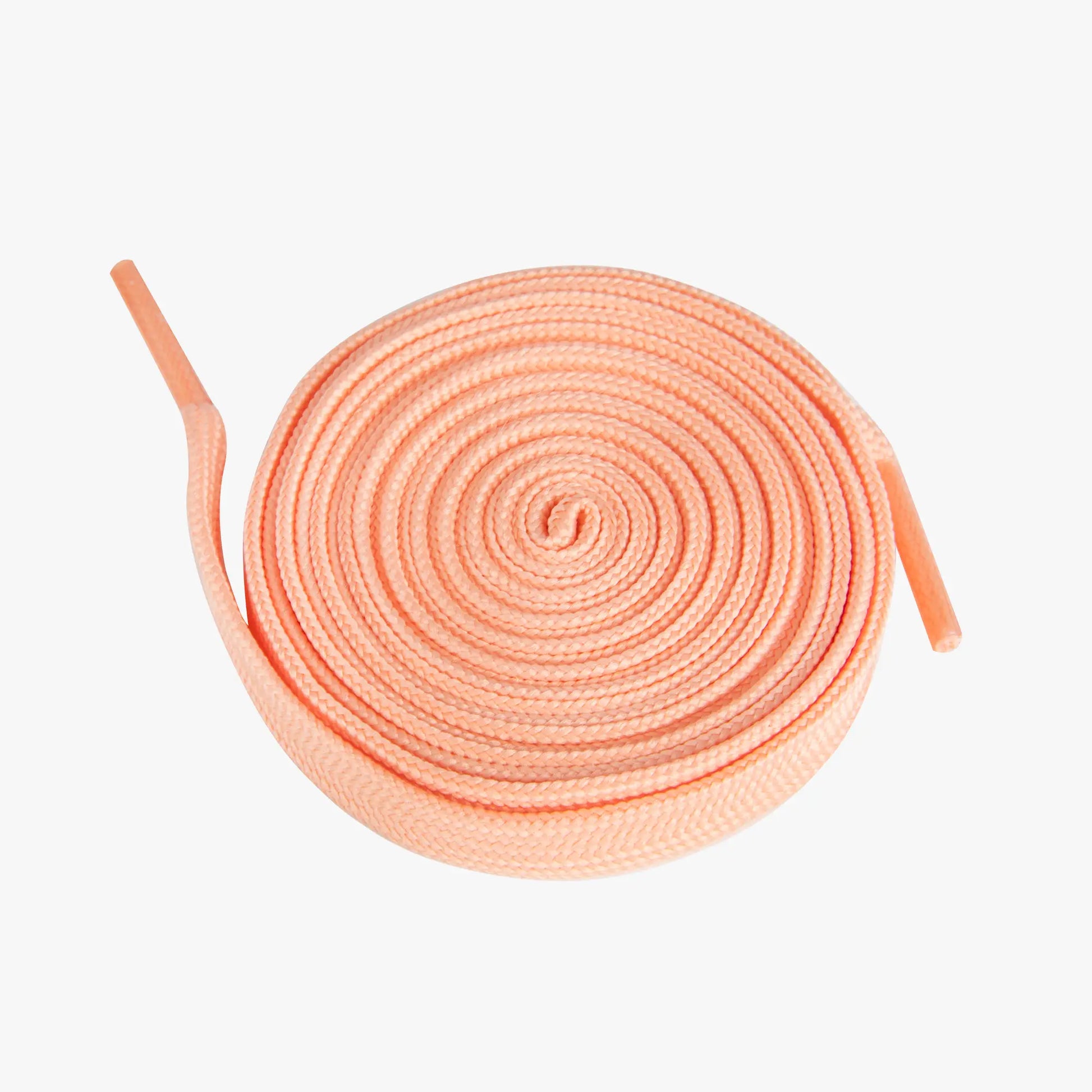 Round coil of peach-colored shoelaces on a white background