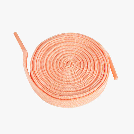 Round coil of peach-colored shoelaces on a white background