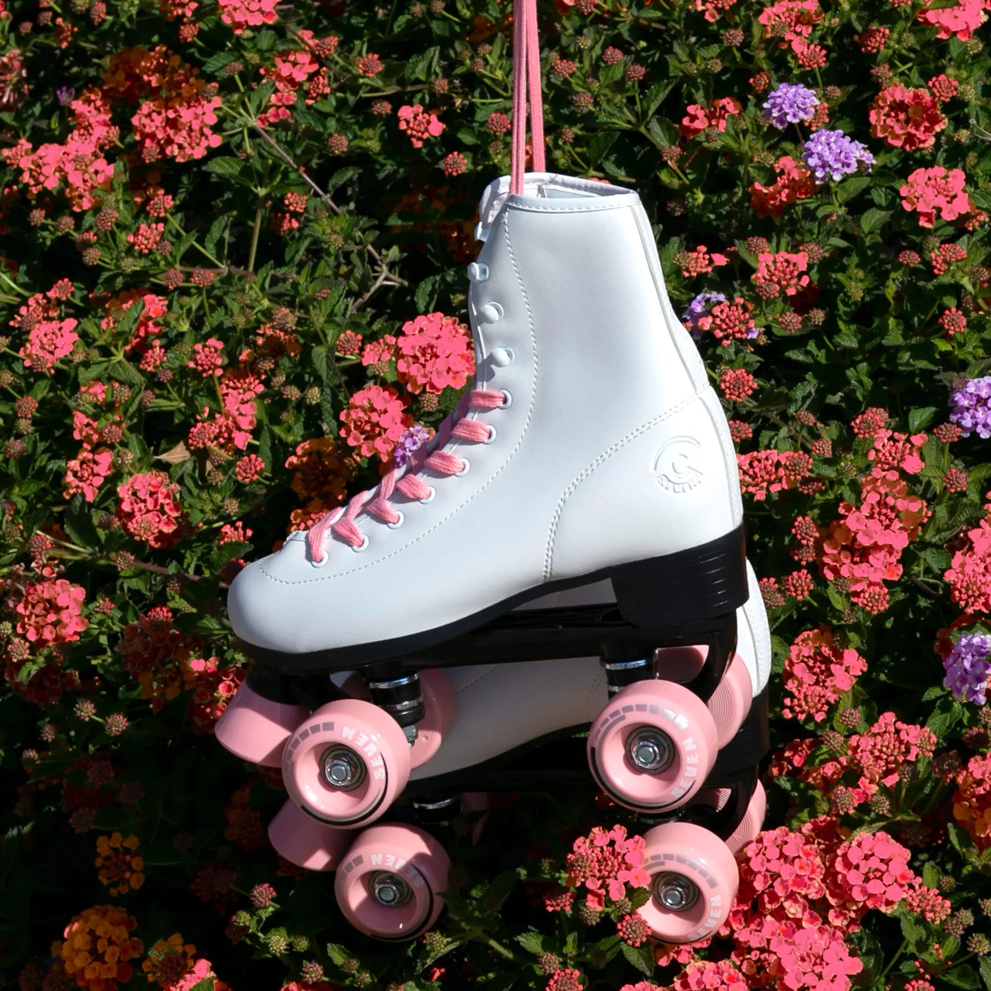 White roller skate with pink wheels hanging among flowers
