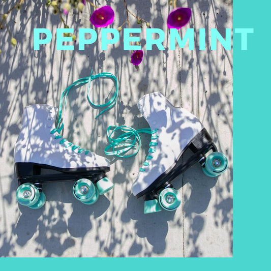 Pair of roller skates with teal wheels on a textured surface with flowers and 'PEPPERMINT' text.