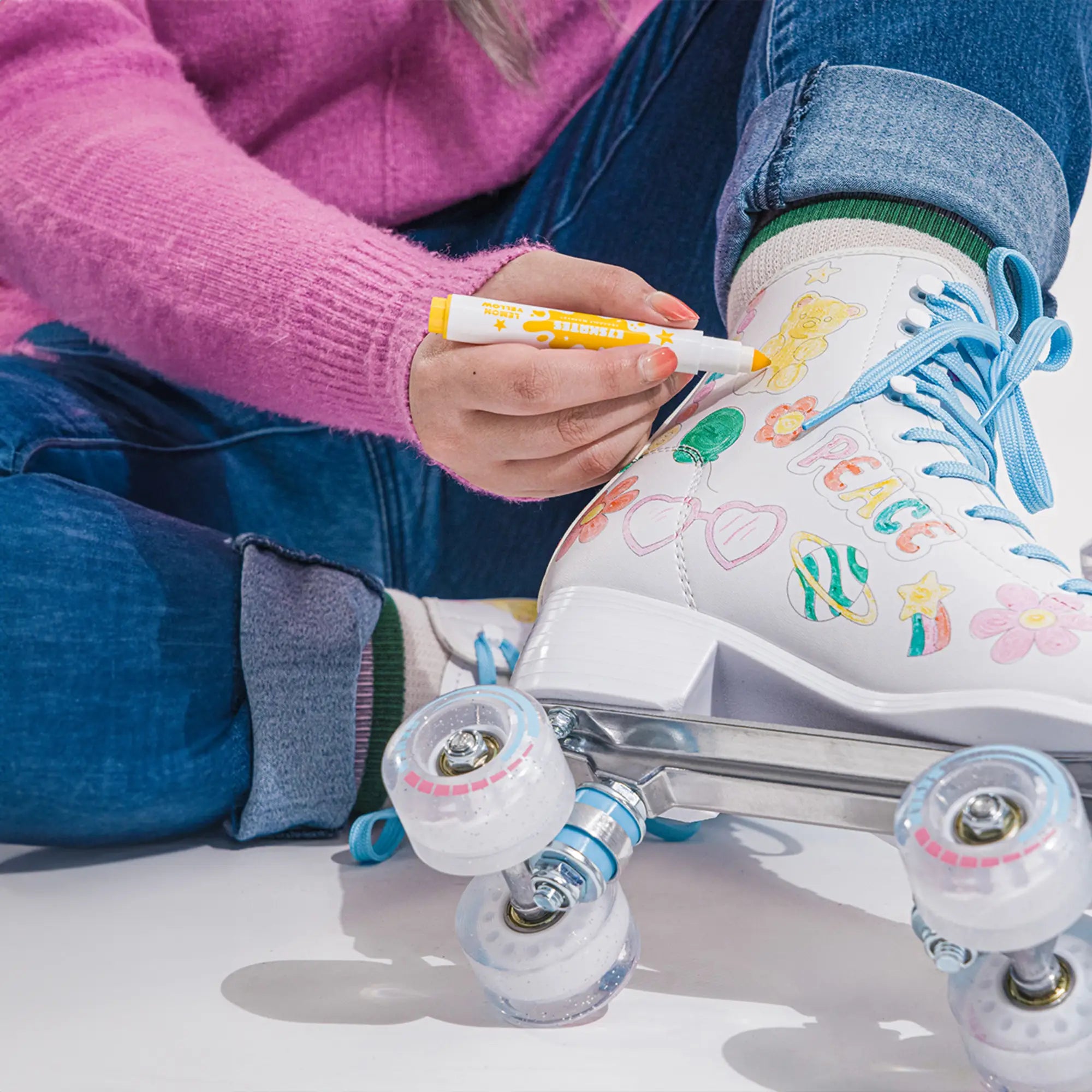Person drawing on a white roller skate with colorful markers.
