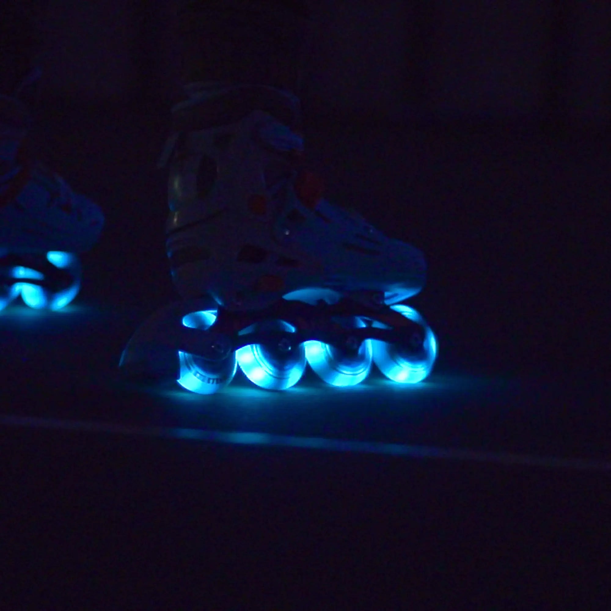 Roller skates with glowing blue wheels in a dark setting