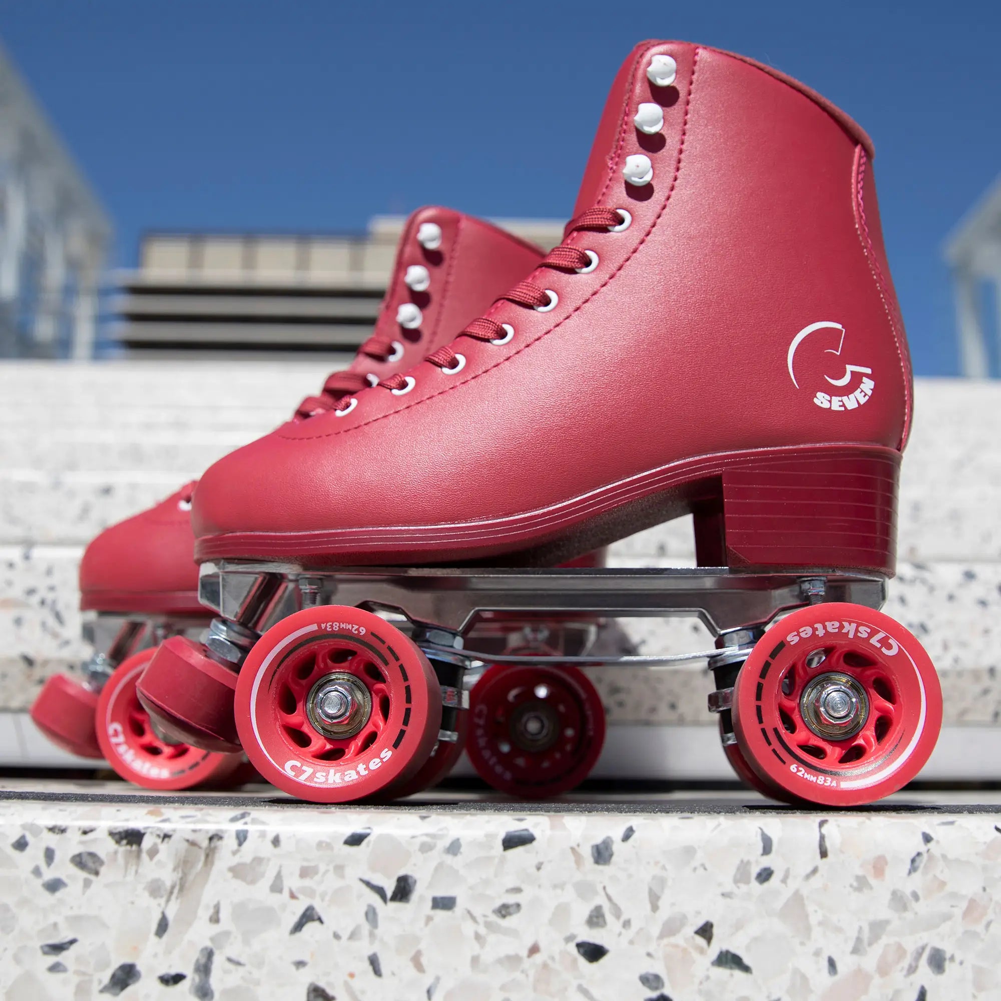 Red roller skates with visible brand logo on a concrete surface with blue sky background