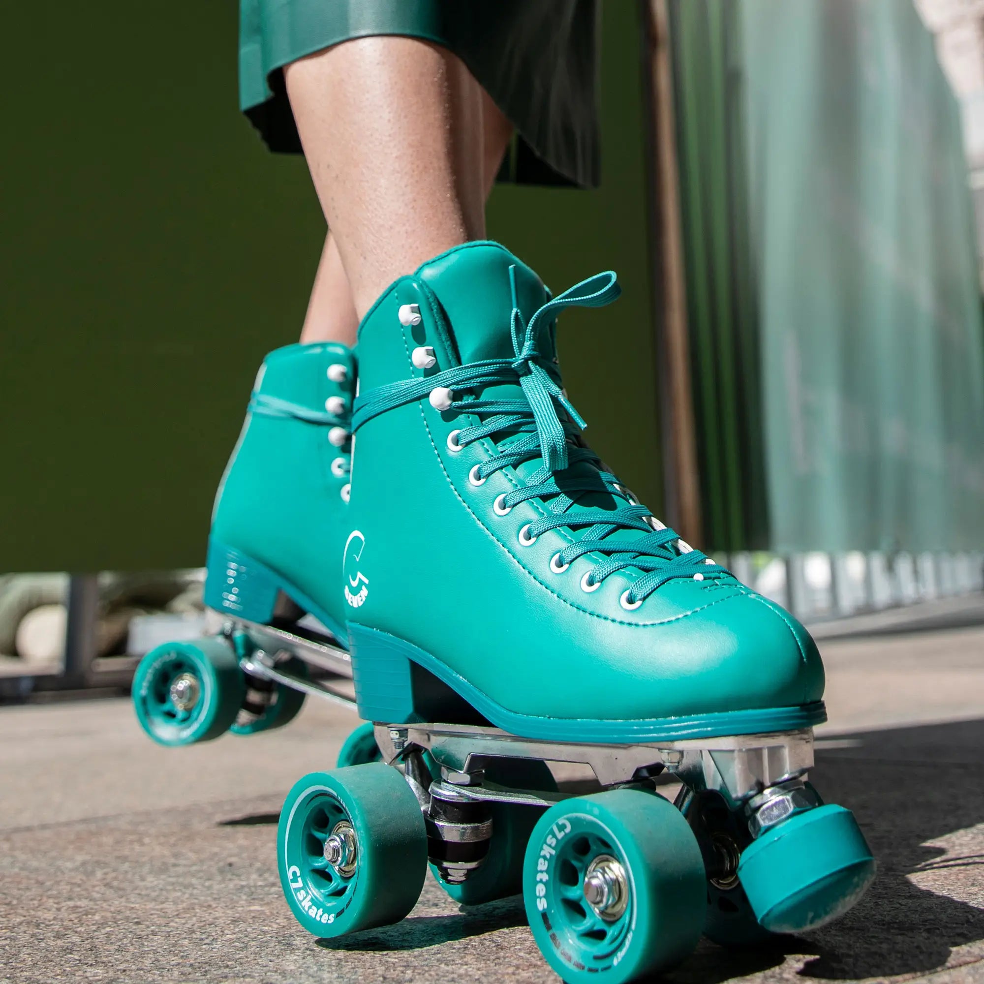 Teal roller skates worn by a person on a blurred background
