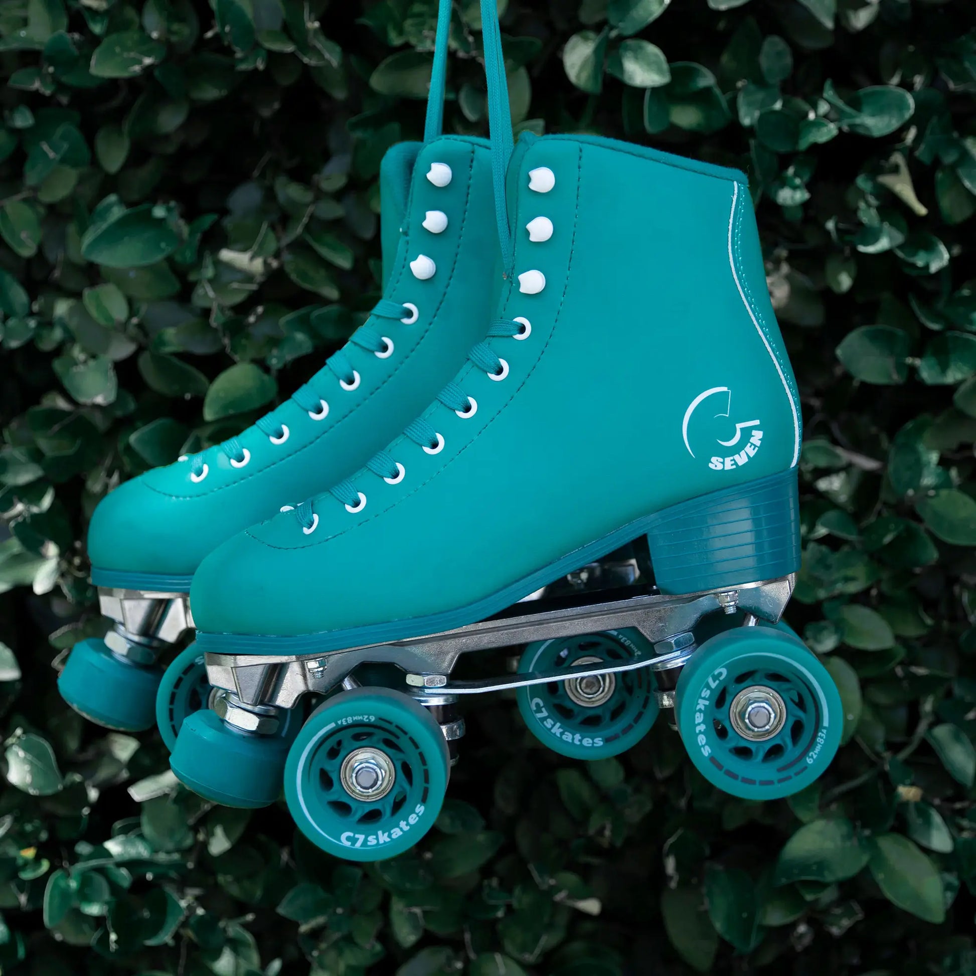 Turquoise roller skates with visible brand logo on a green leafy background
