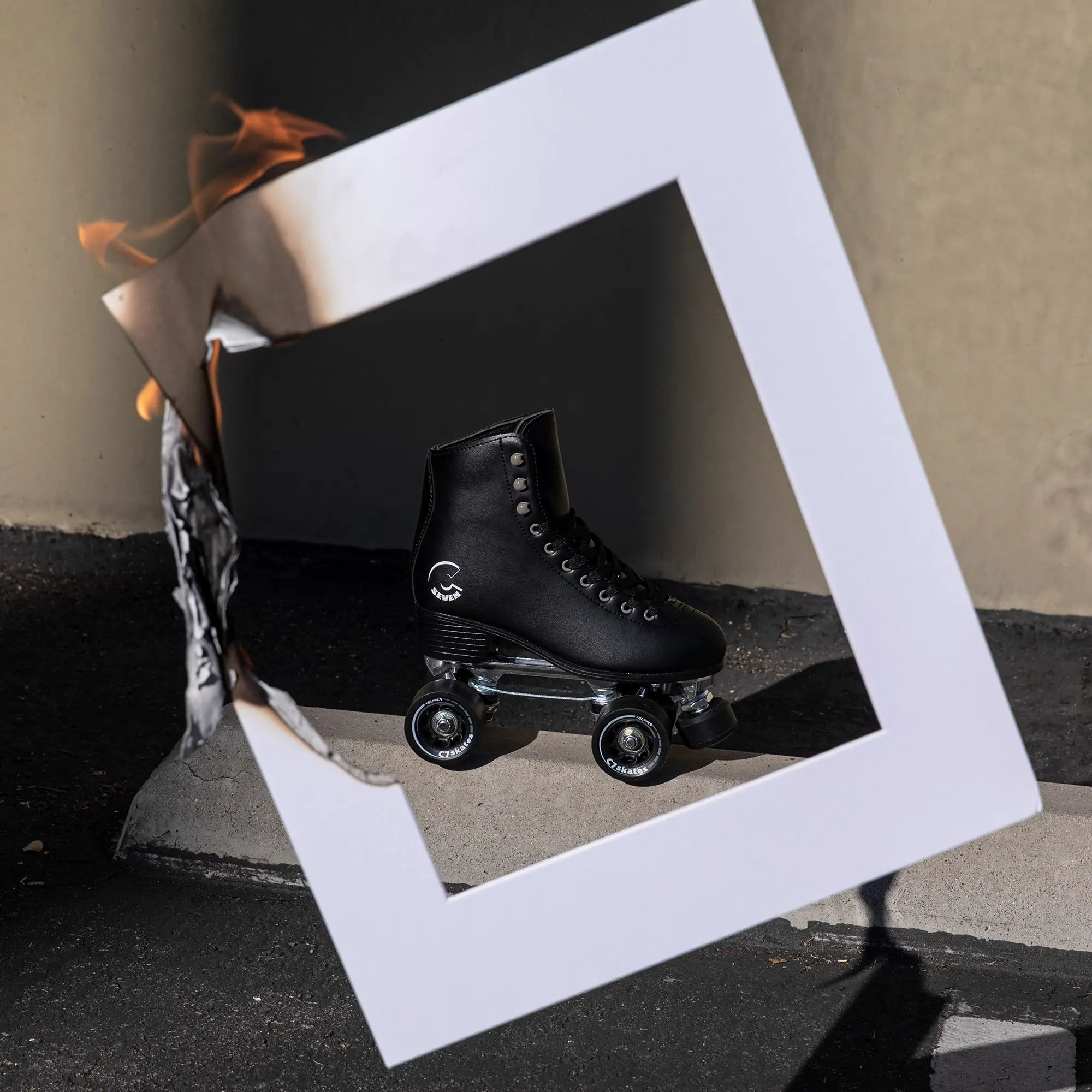Black roller skate on a reflective surface with a white geometric frame and abstract elements.