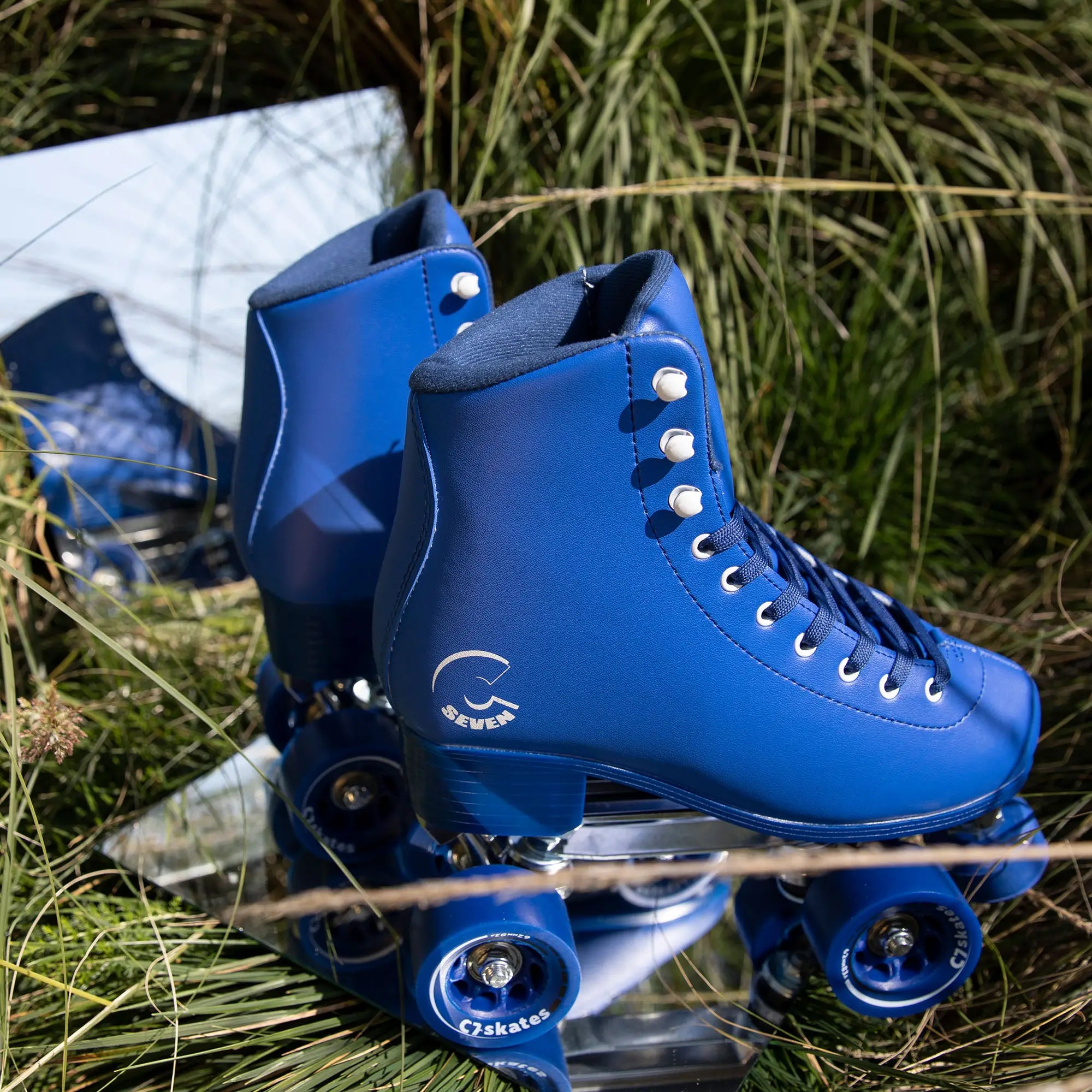 Blue roller skates with white laces on grass