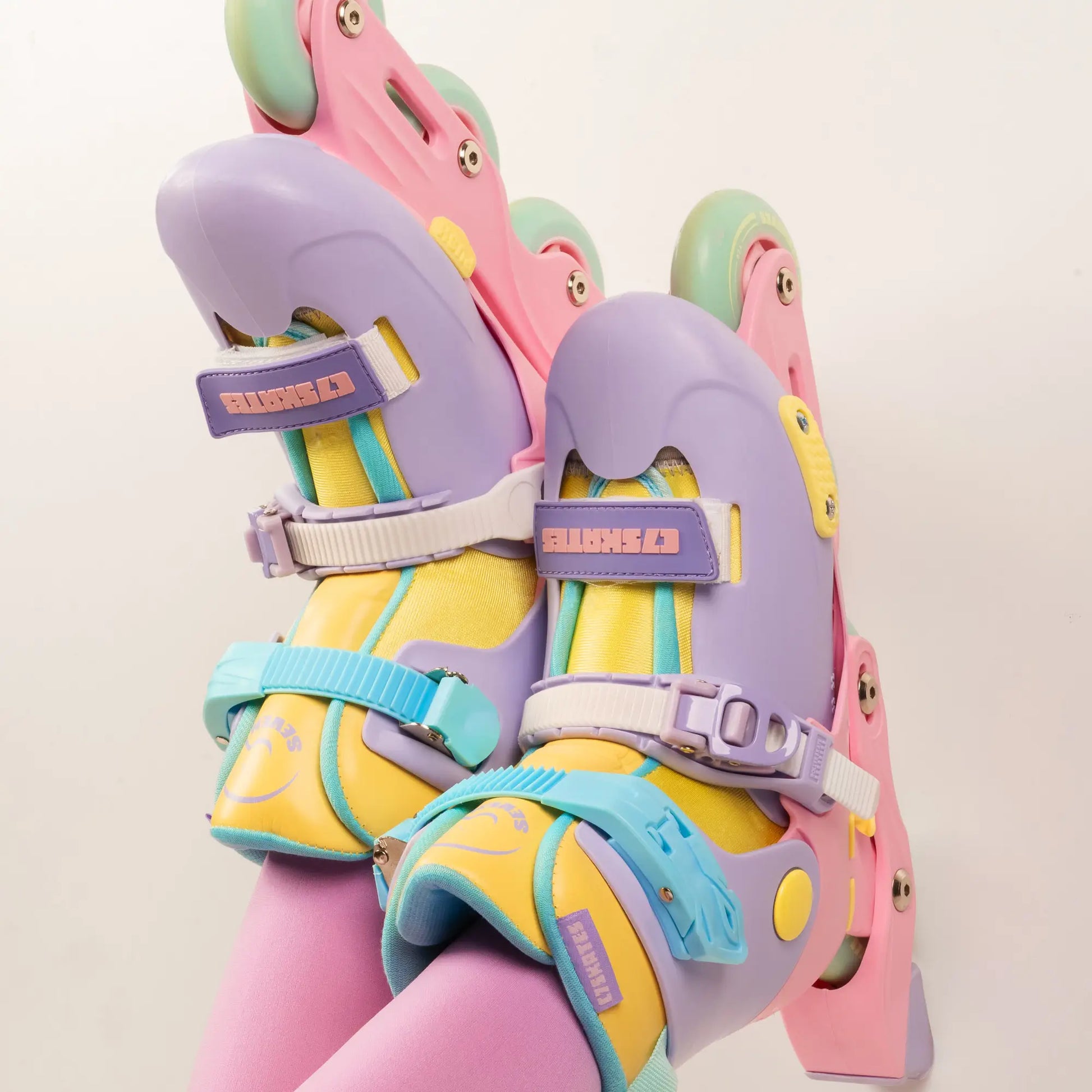 Colorful inline skates with pastel pink, yellow, and purple design on a light background