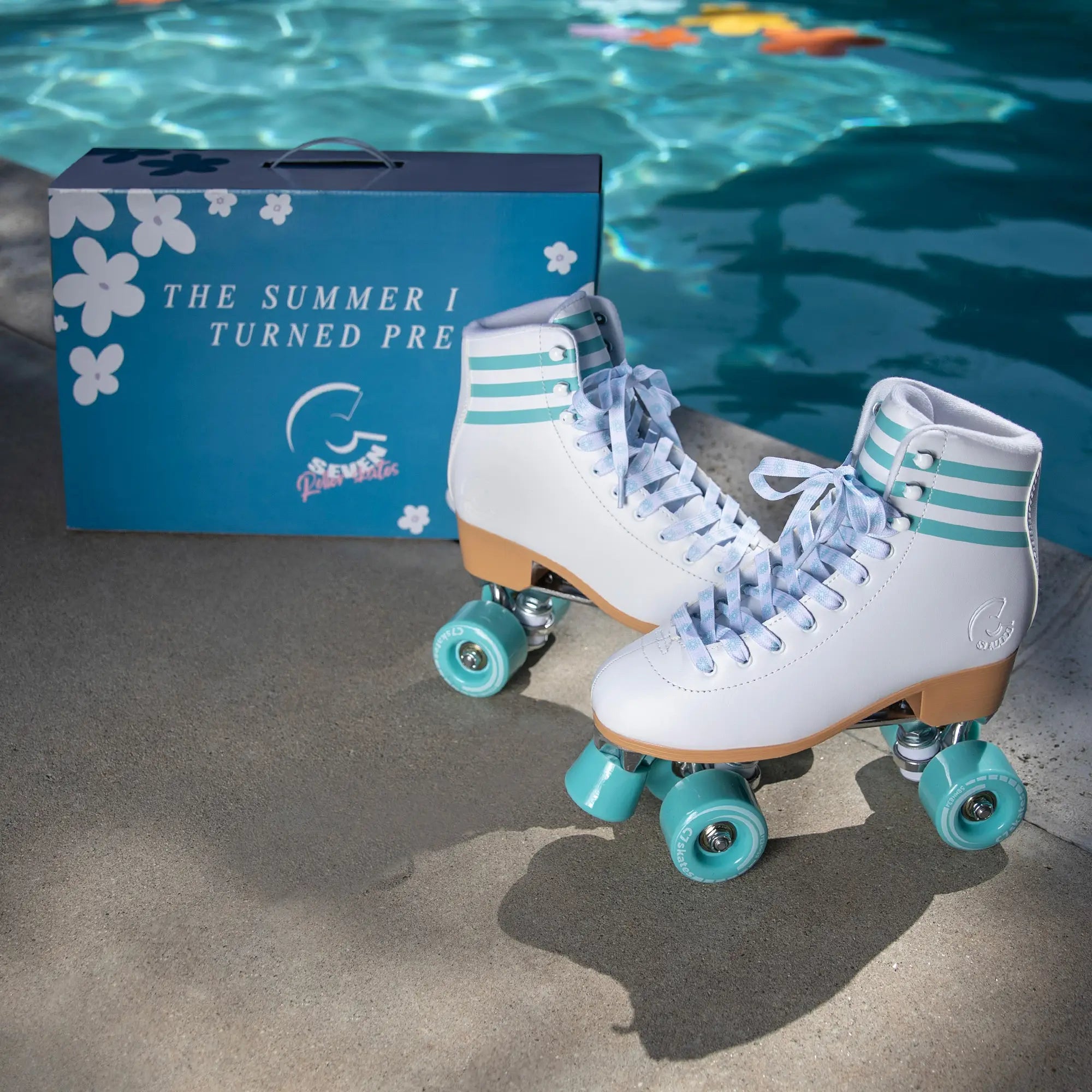 White roller skates with turquoise wheels next to a blue box by a pool