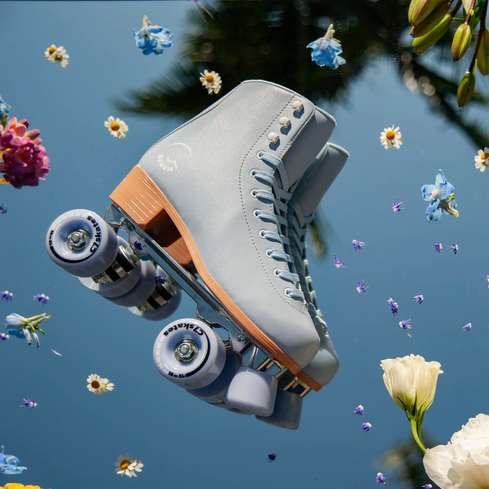 Gray roller skate with light blue wheels against a blue sky with flowers