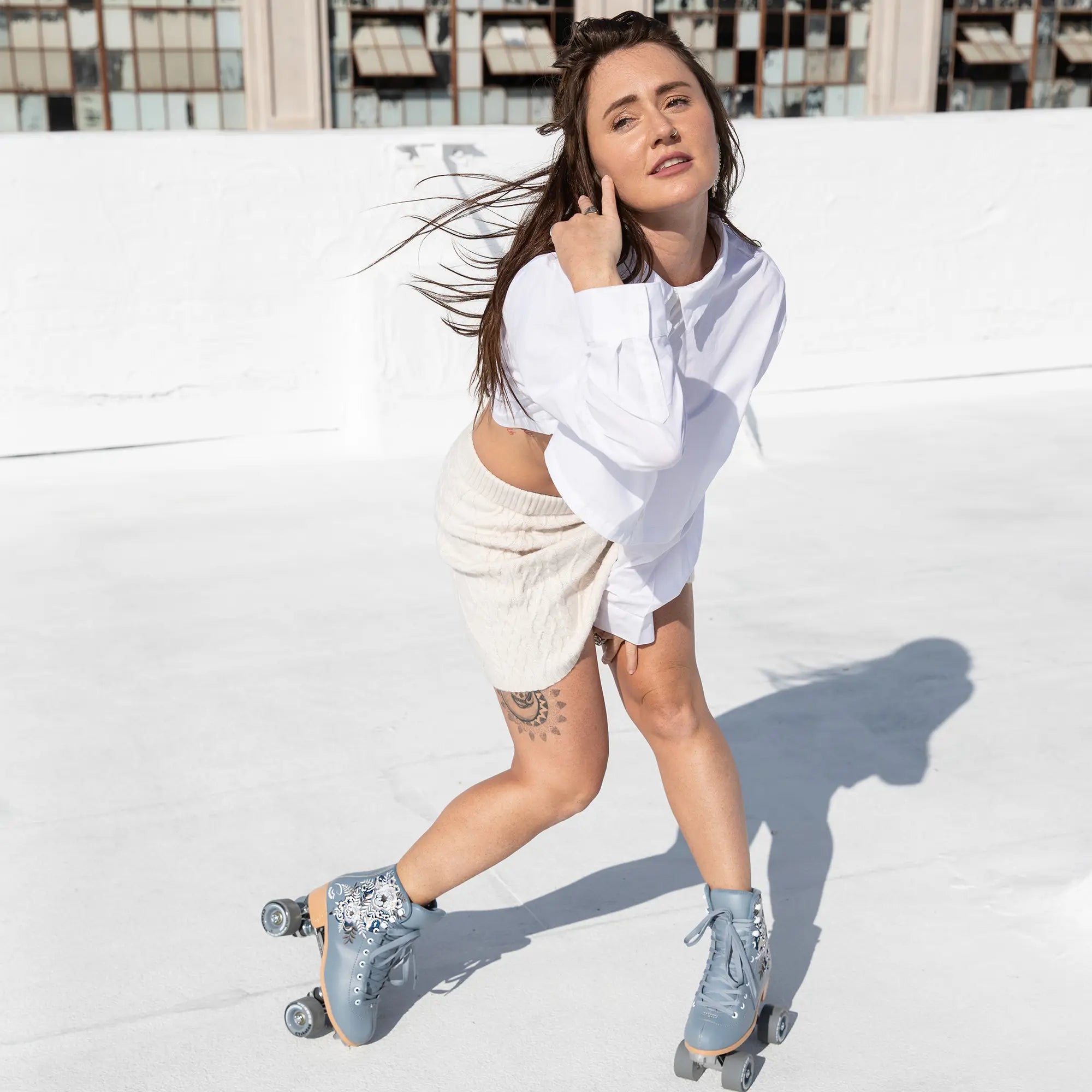 Woman in white shirt and shorts with roller skates on a white background