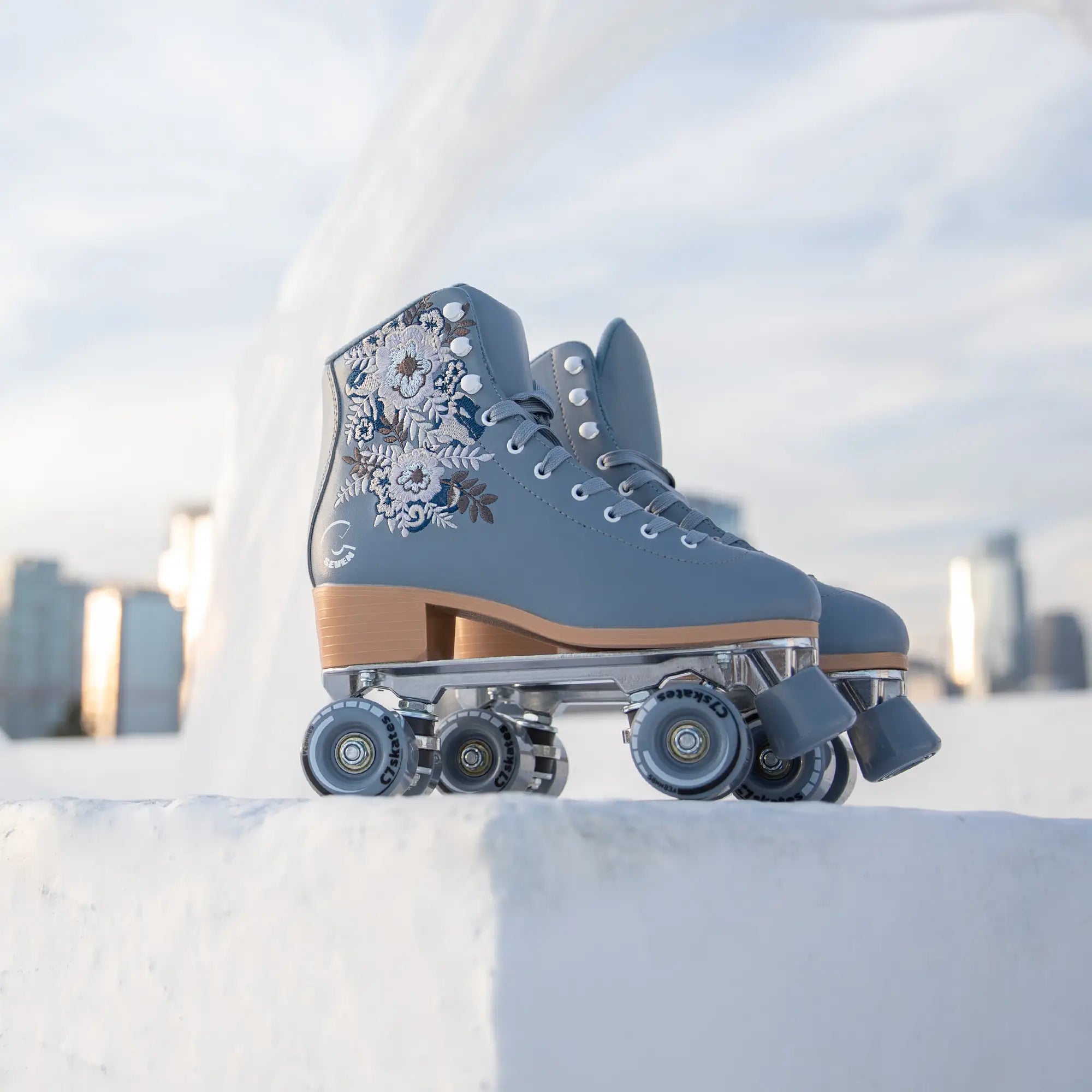 Pair of blue roller skates with floral design on a snowy background