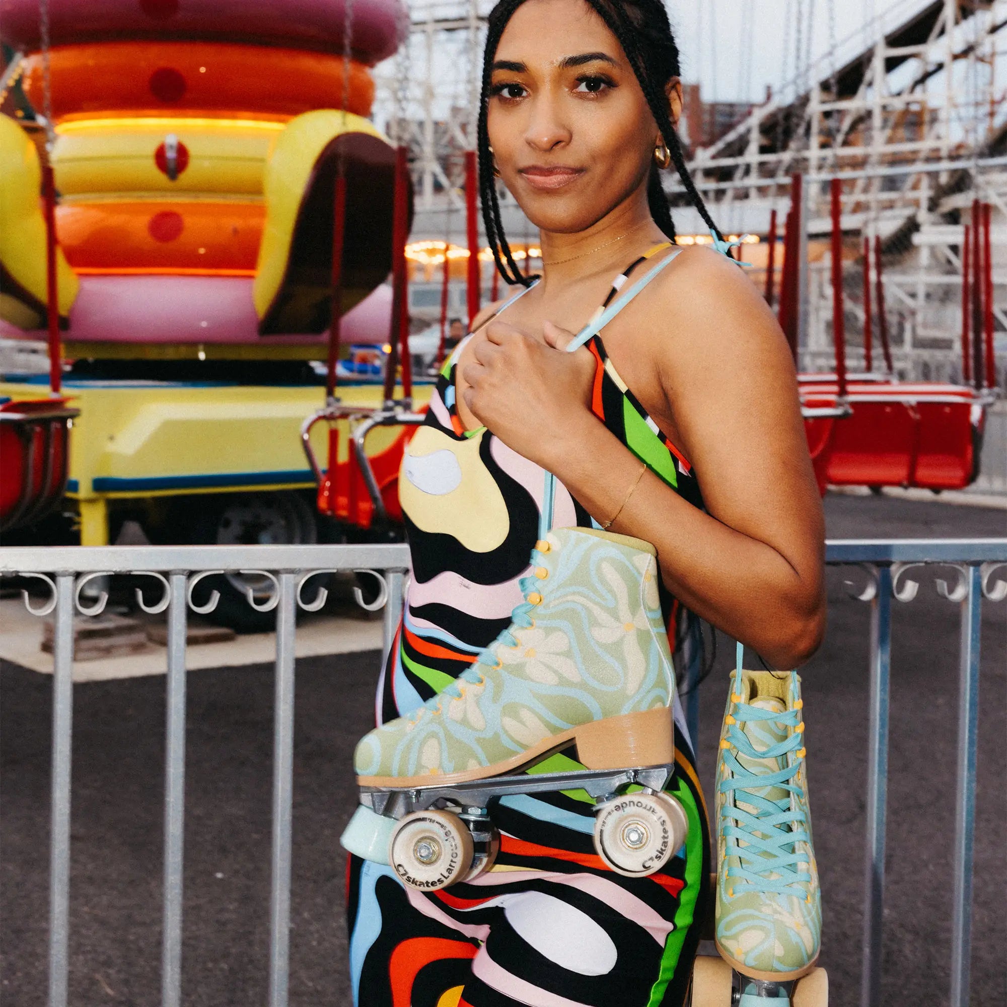 Woman holding a colorful roller skirt with a vibrant background of amusement park rides.