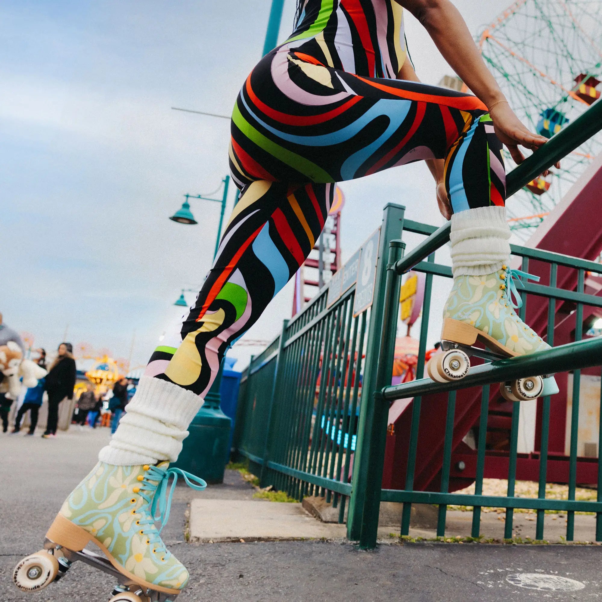 Person wearing colorful striped leggings and roller skates at an amusement park.