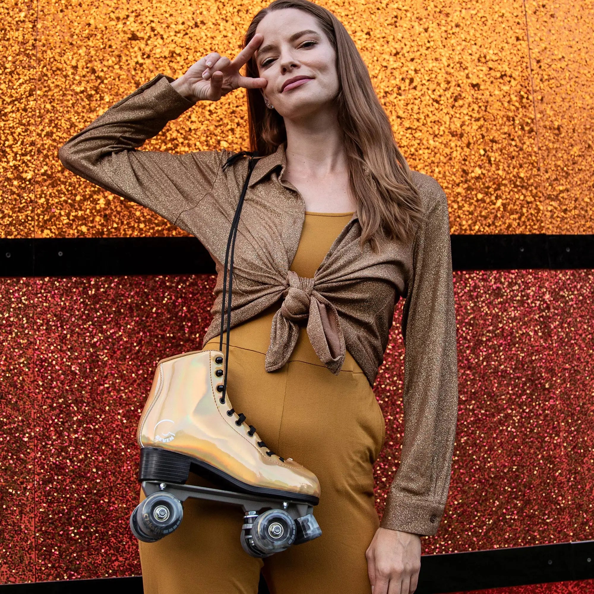 Woman posing with a gold roller shoe against a glittery red and orange background