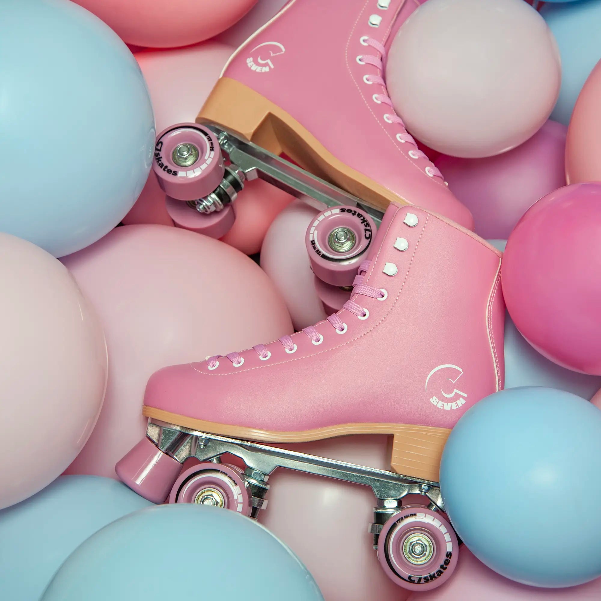 Pink roller skate surrounded by pink and blue balloons
