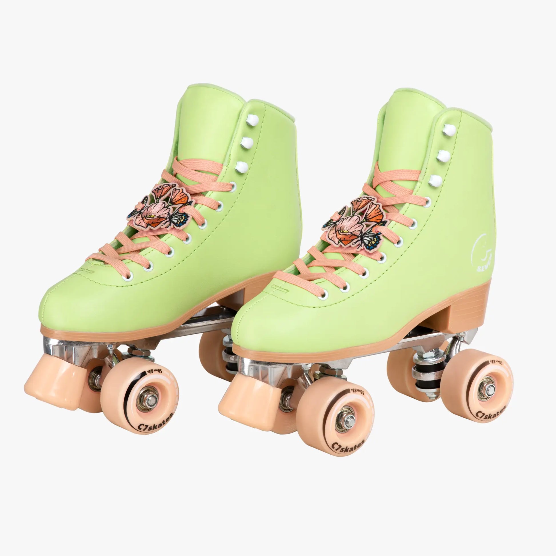 Pair of light green roller skates with peach laces on a white background