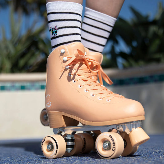 peach roller skates with clear wheels worn by a person on a pool deck.