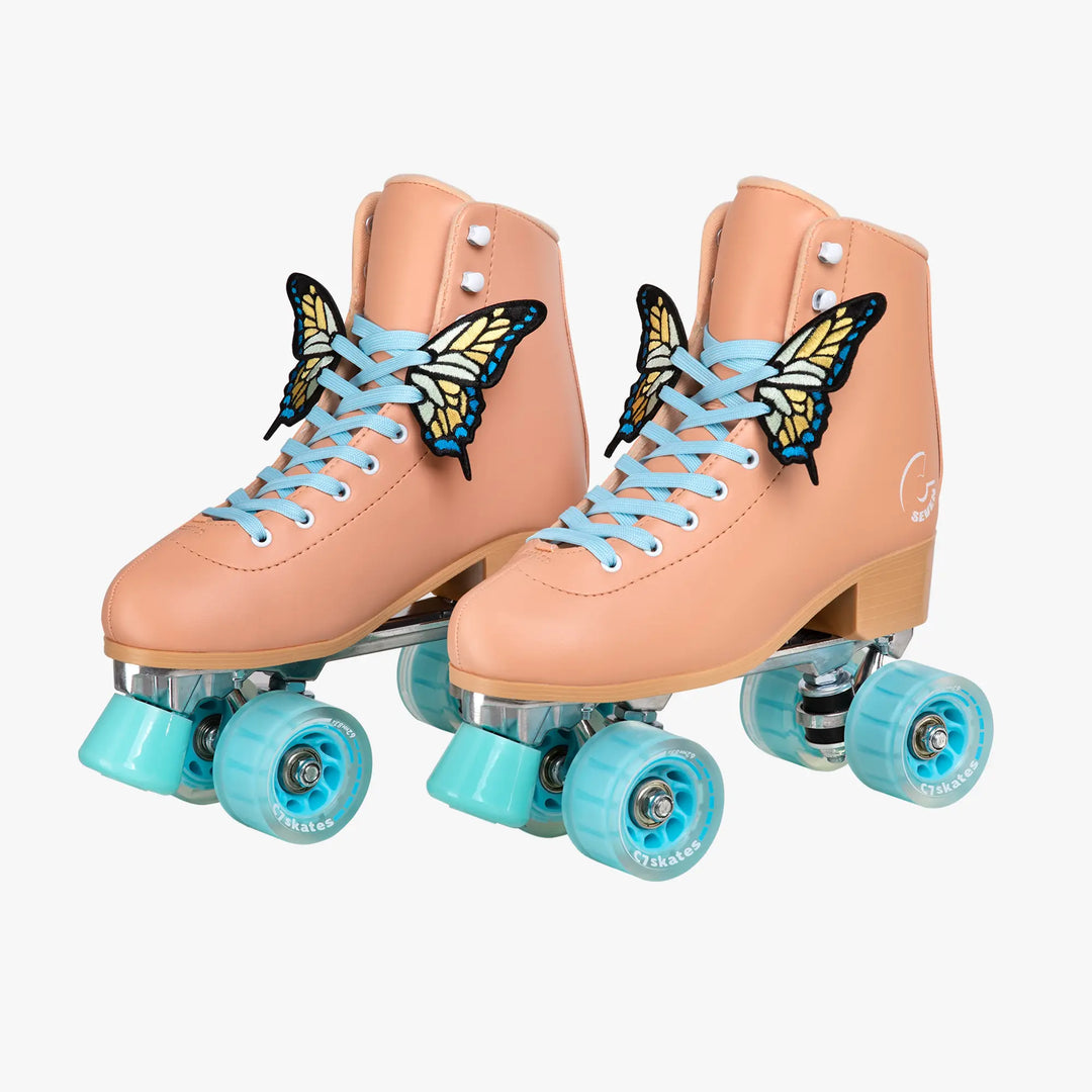 Pair of peach-colored roller skates with butterfly decorations and turquoise wheels on a white background