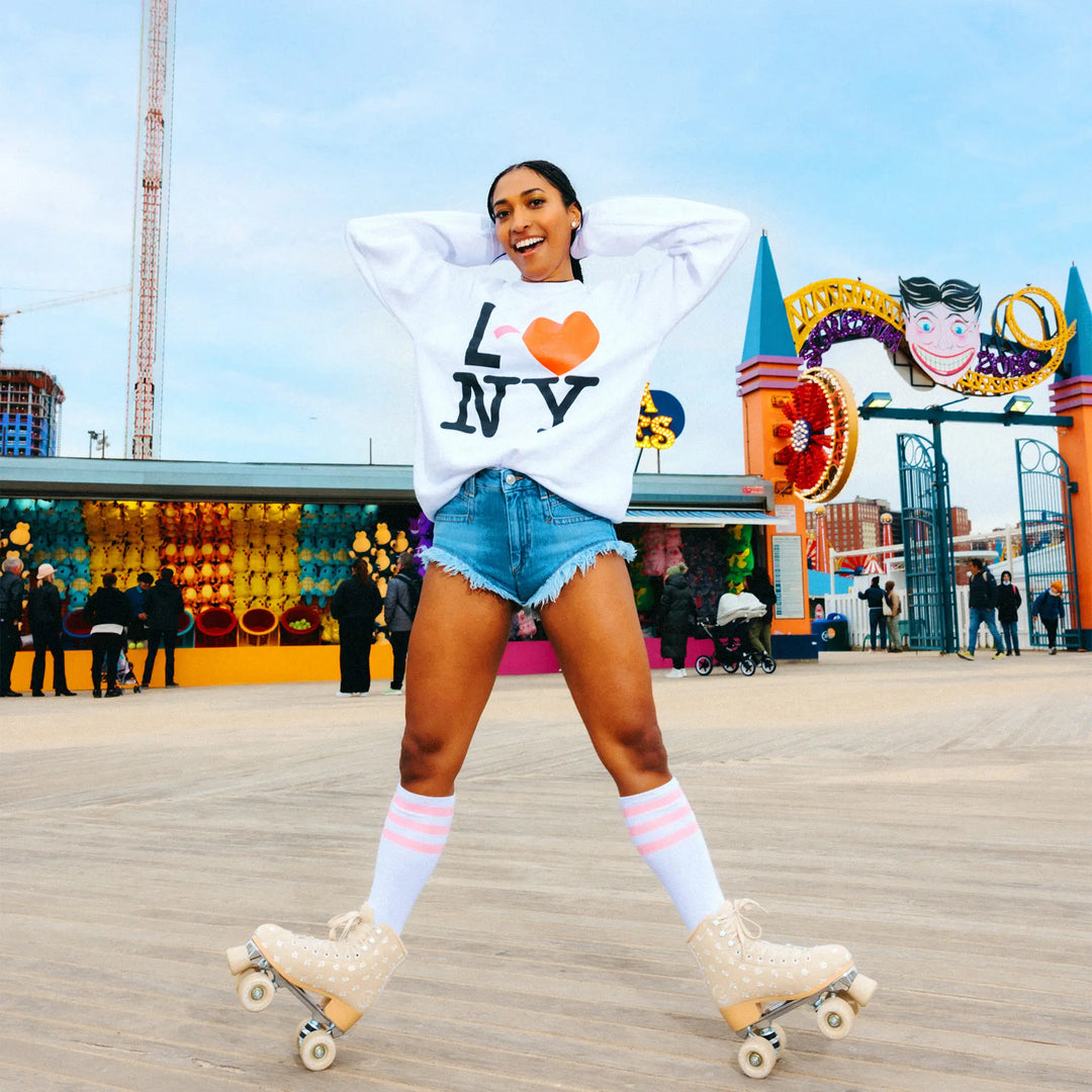Woman roller skating on a boardwalk with colorful decorations and people in the background