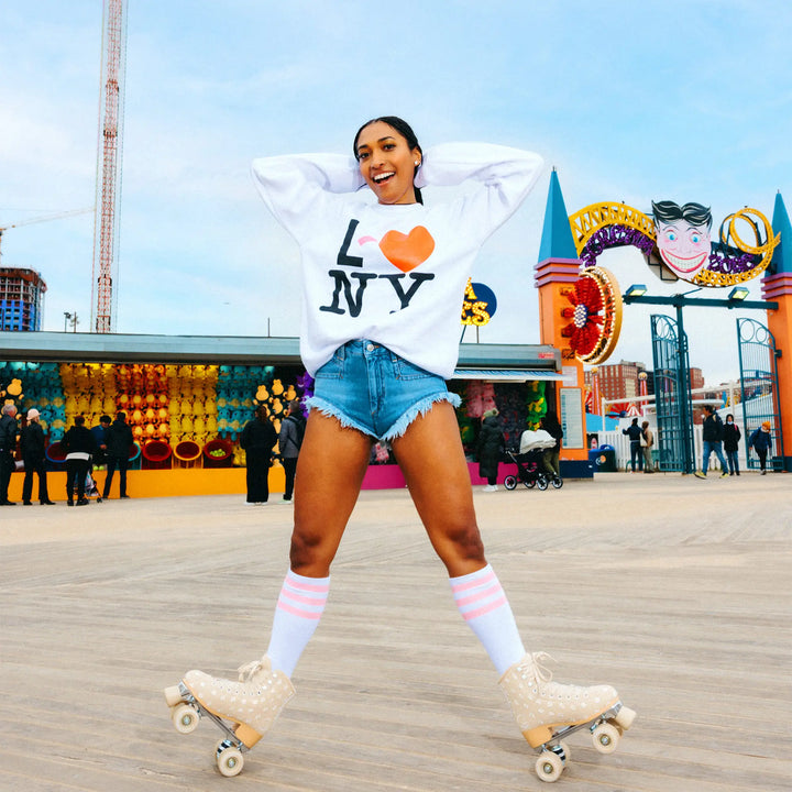 Woman roller skating on a boardwalk with colorful decorations and people in the background