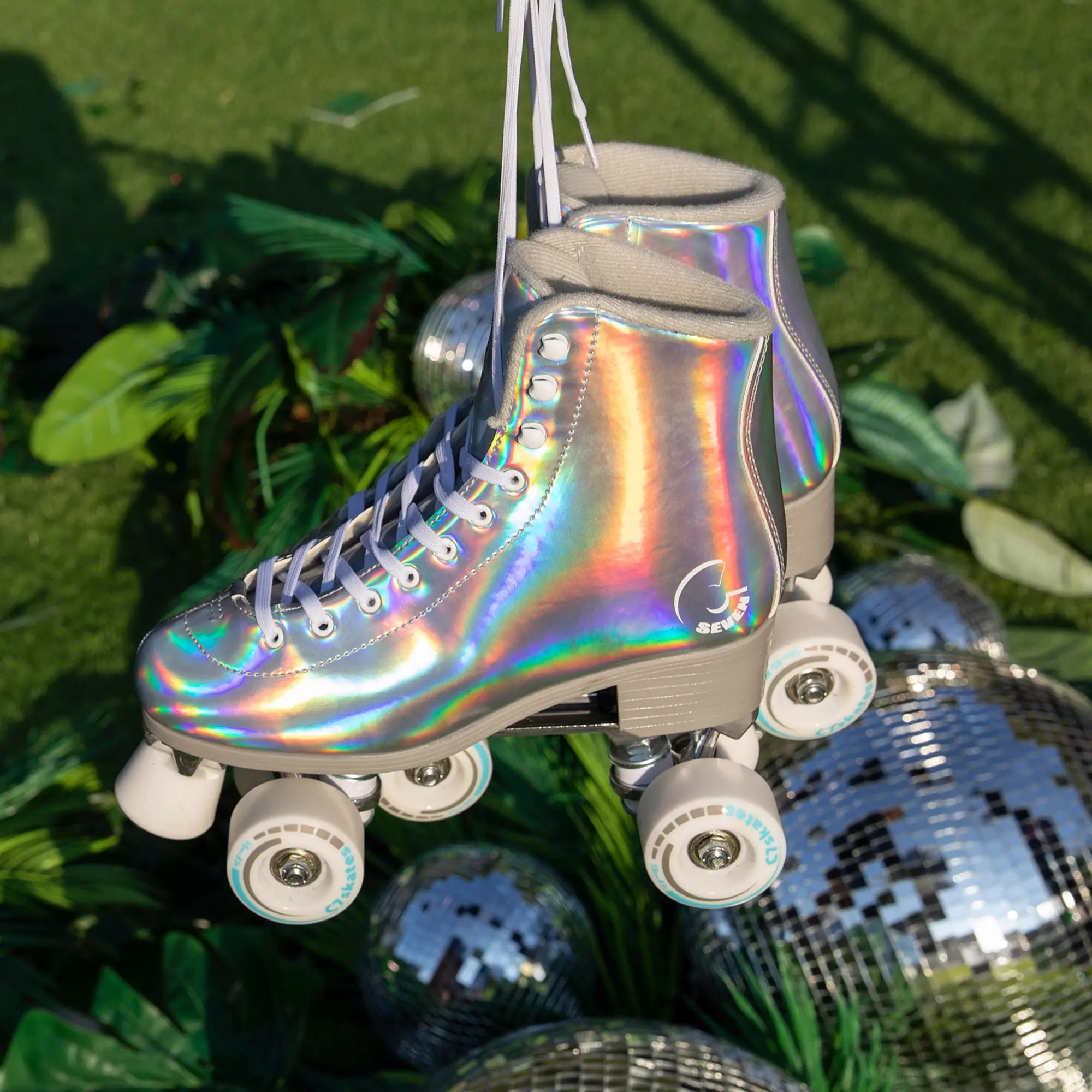 Holographic roller skate hanging on a grassy background with disco balls.