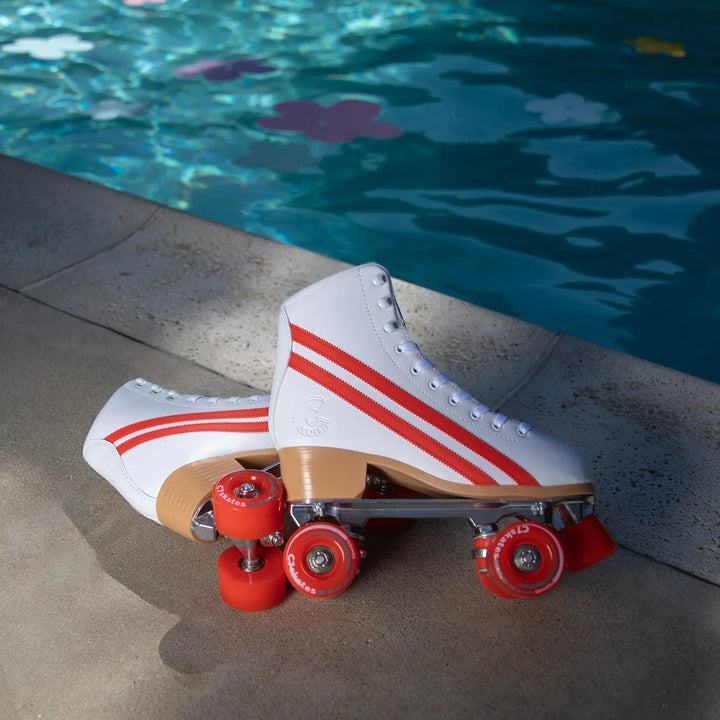 White roller skate with red stripes and wheels by a pool