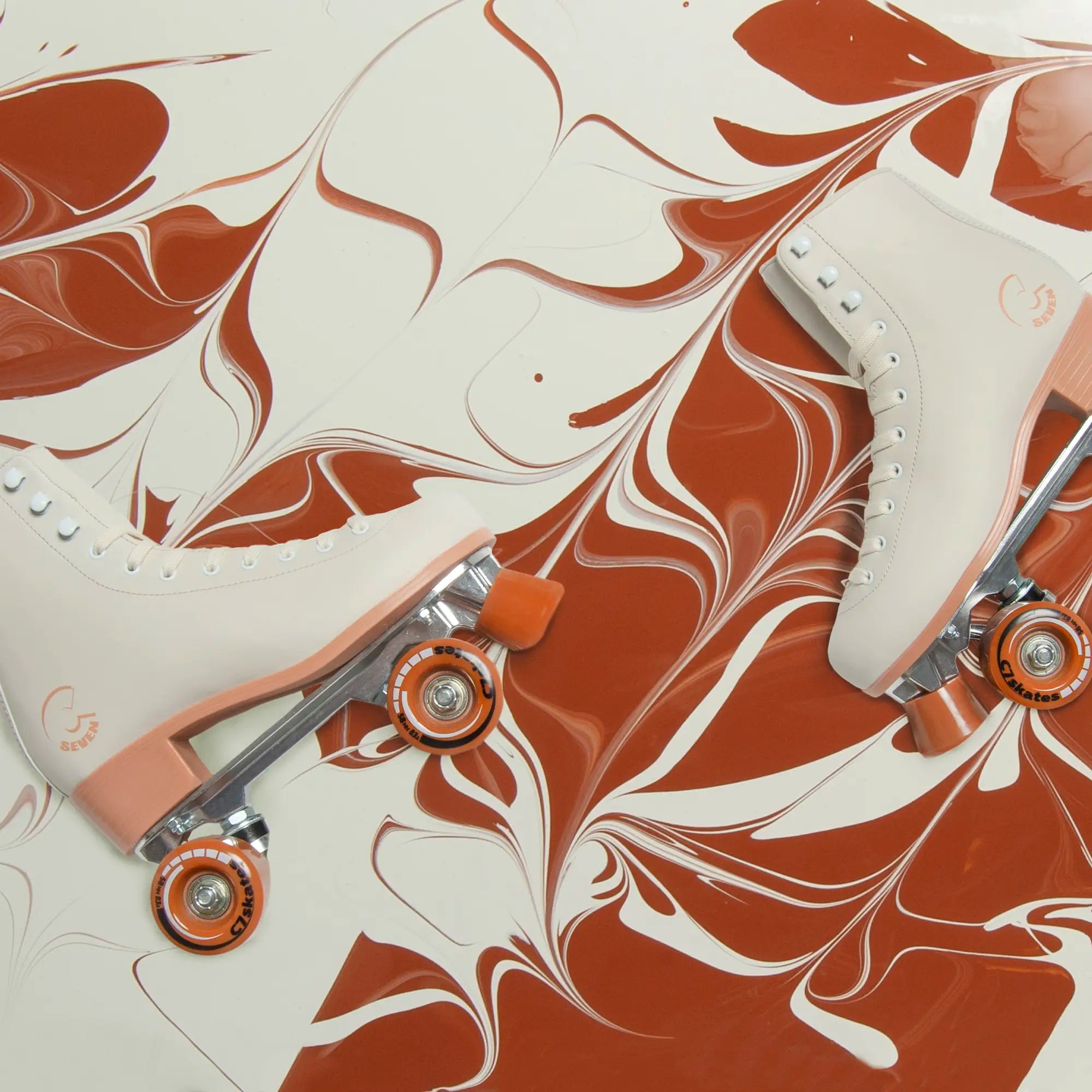 Marbled brown and white roller skates with orange wheels on a matching background