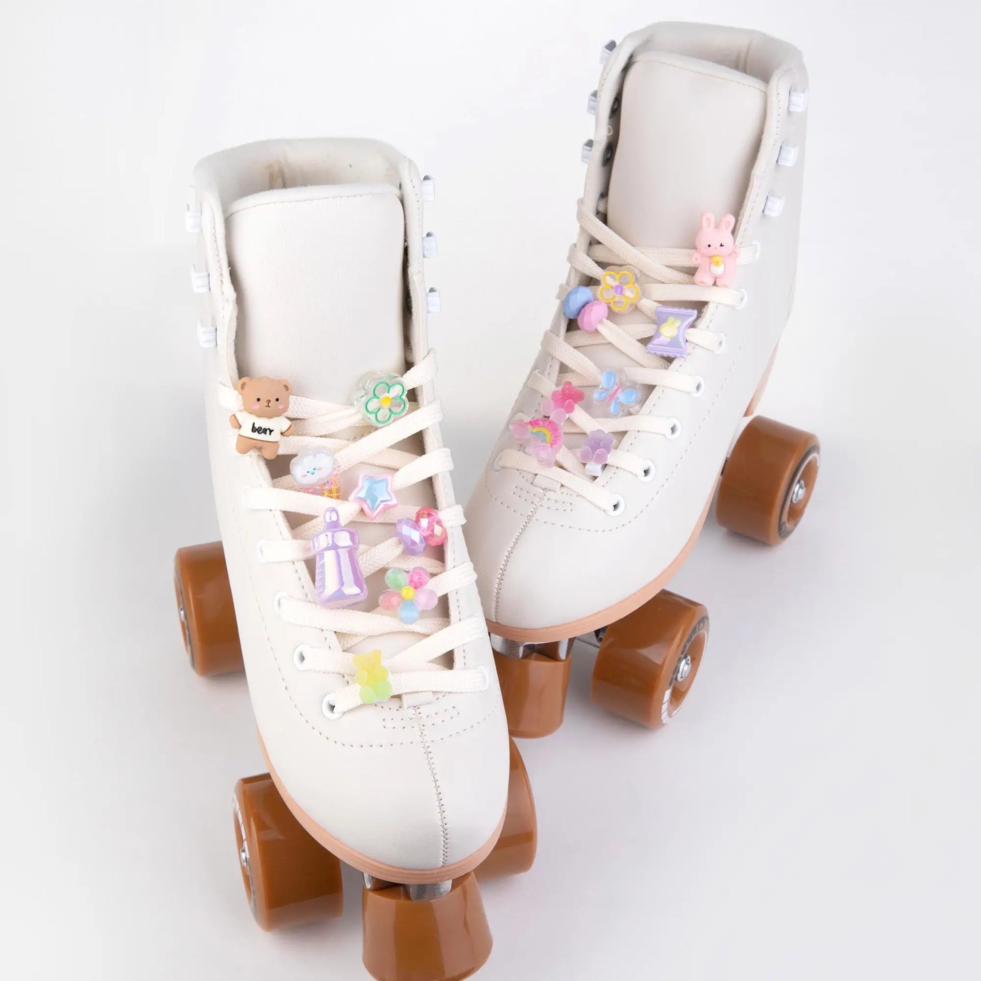 White roller skates with decorative laces with charms and brown wheels on a light gray background