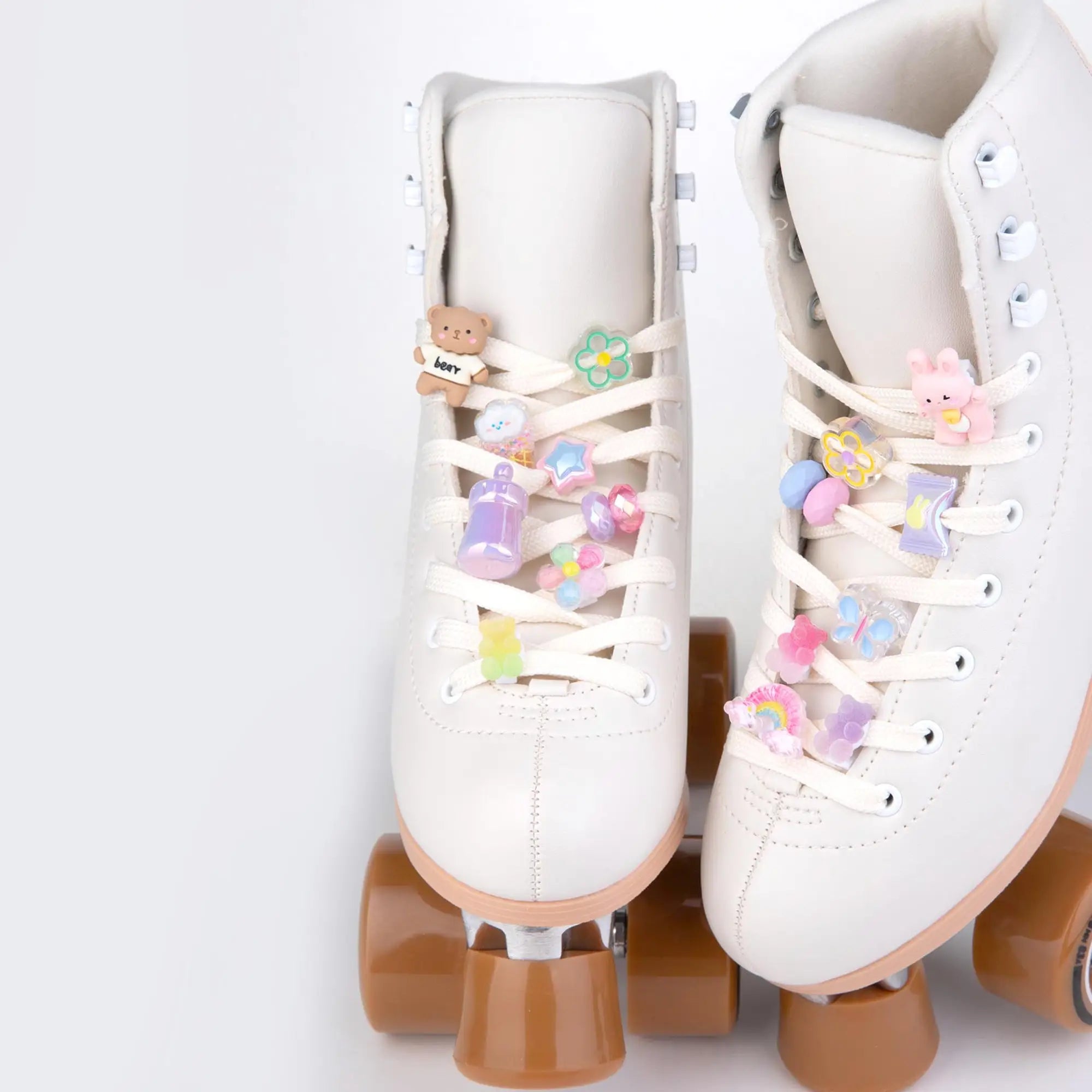 White roller skates with decorative laces charms on a light gray background