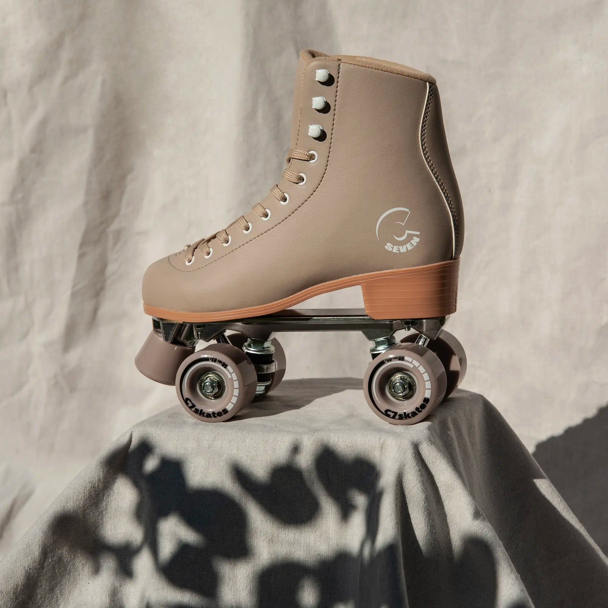 Beige roller skate with brand logo on a textured surface