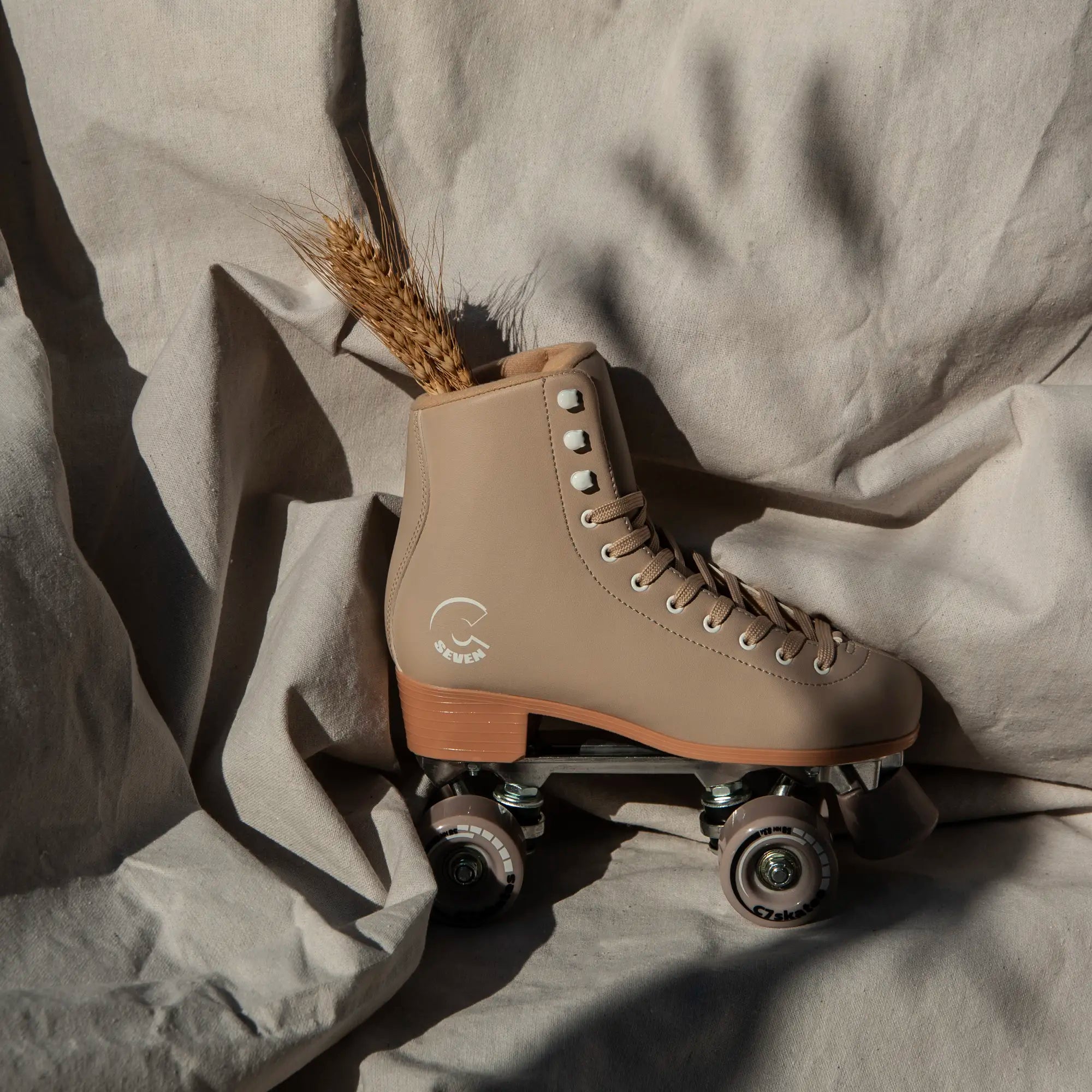 Beige roller skate with a small bouquet of wheat on a textured beige fabric background