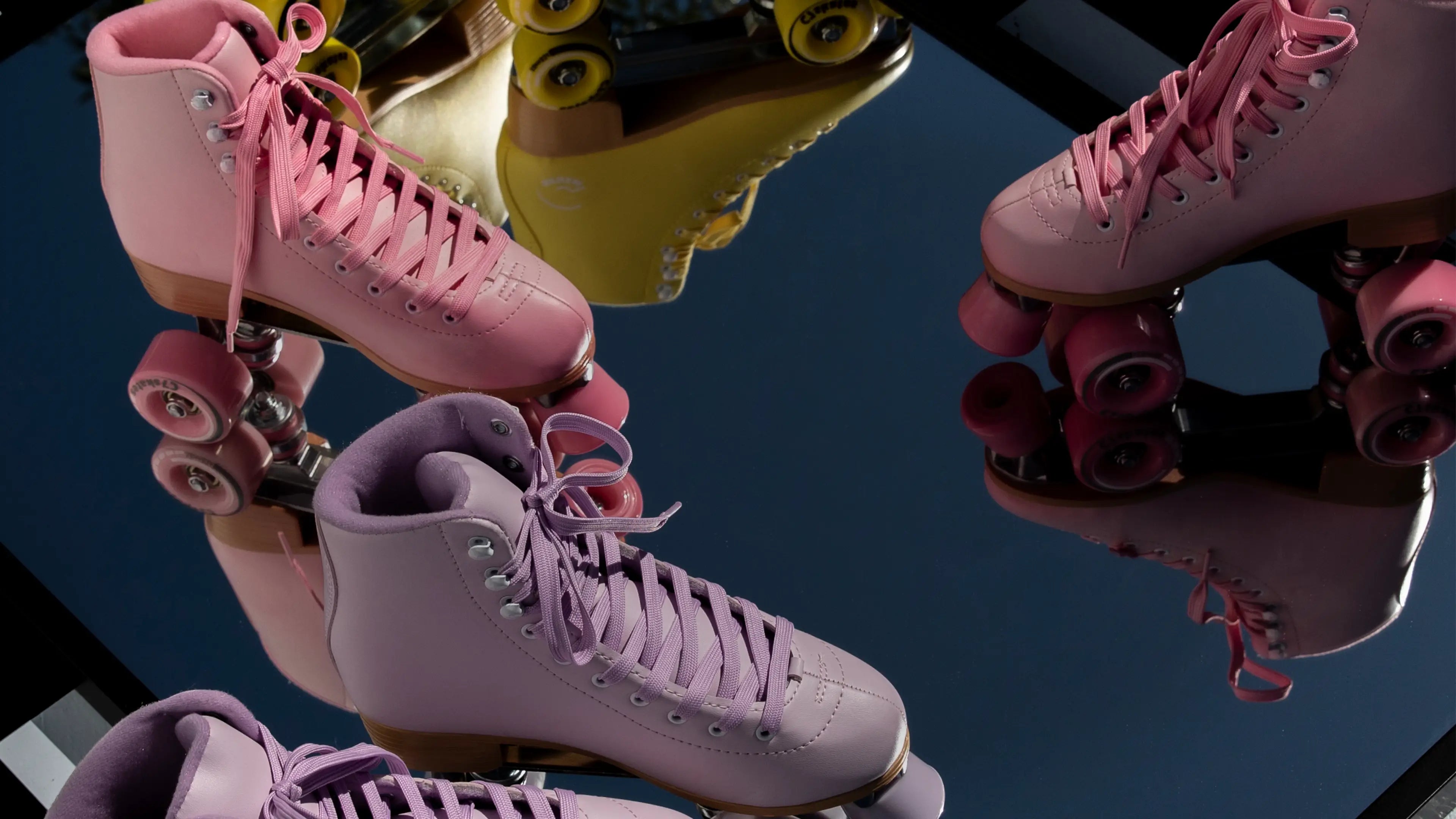 Pink and purple roller skates on a reflective surface